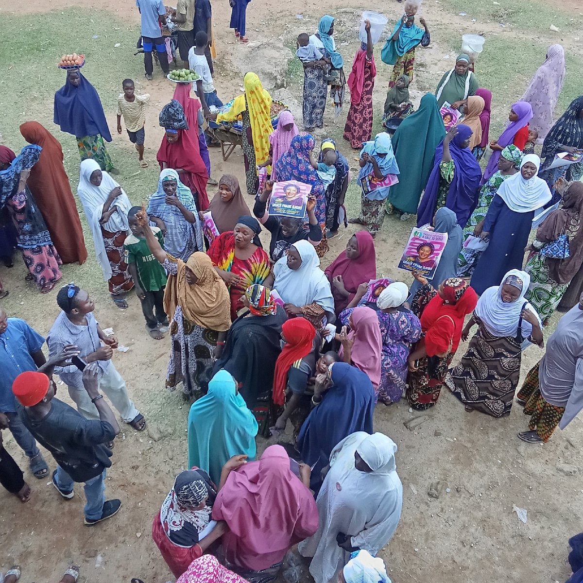 Women gather in dusty open area, location unknown