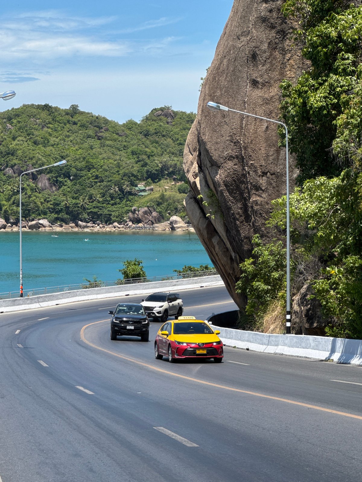 Cruising Ko Samui's scenic coastal road past boulder and bay