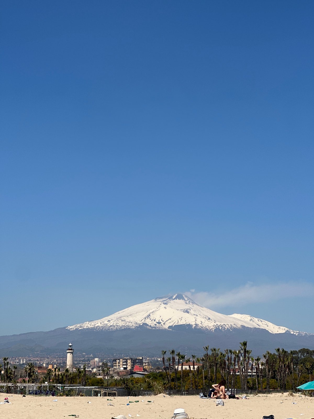 Beachgoers enjoy sunny day in Catania with Mount Etna backdrop