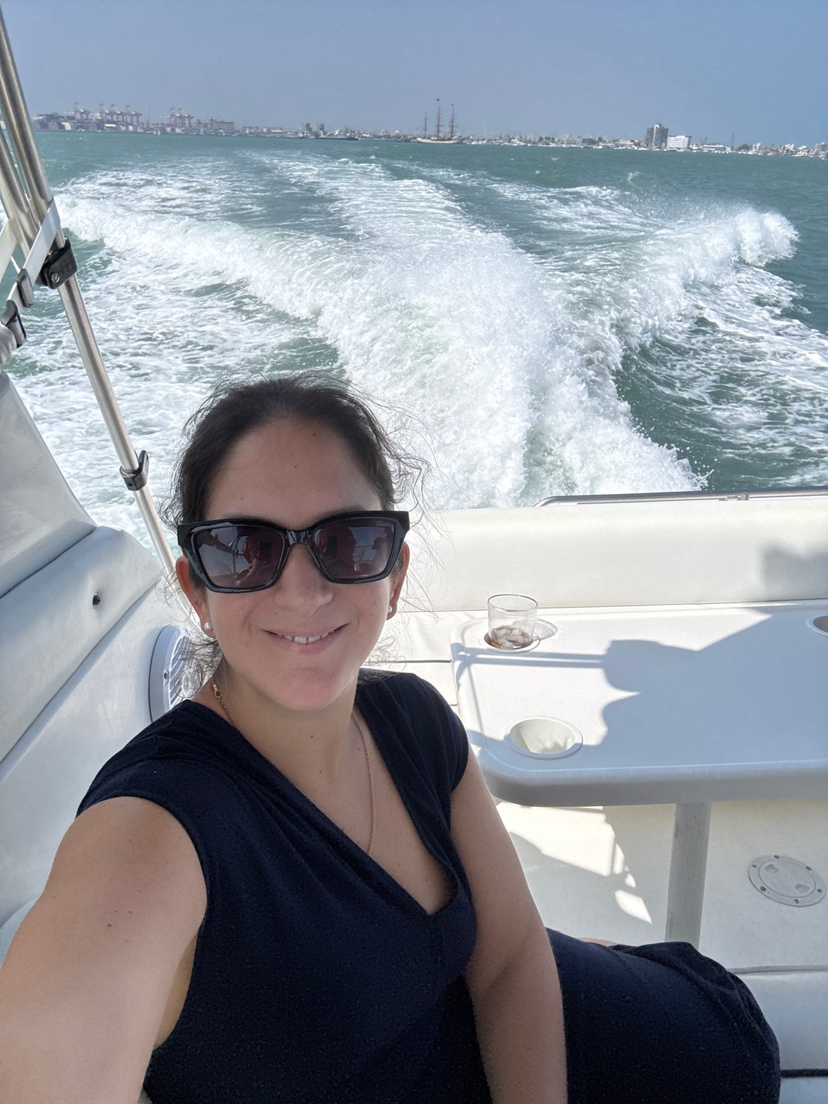 Woman takes boat selfie near anchored sailboats in Peru