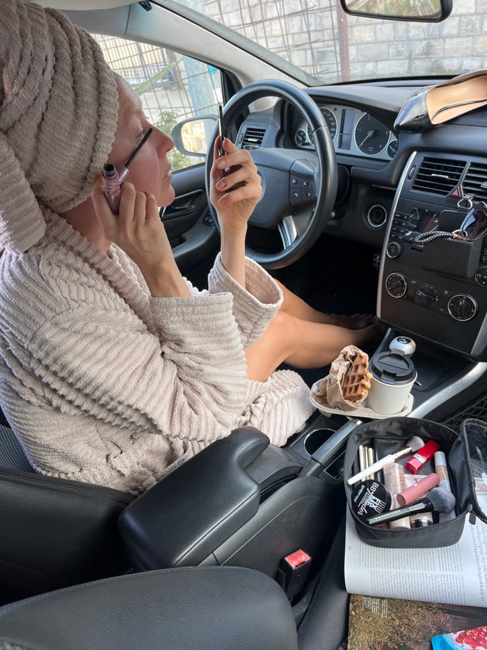 Person in bathrobe does makeup, meets cats in Budva