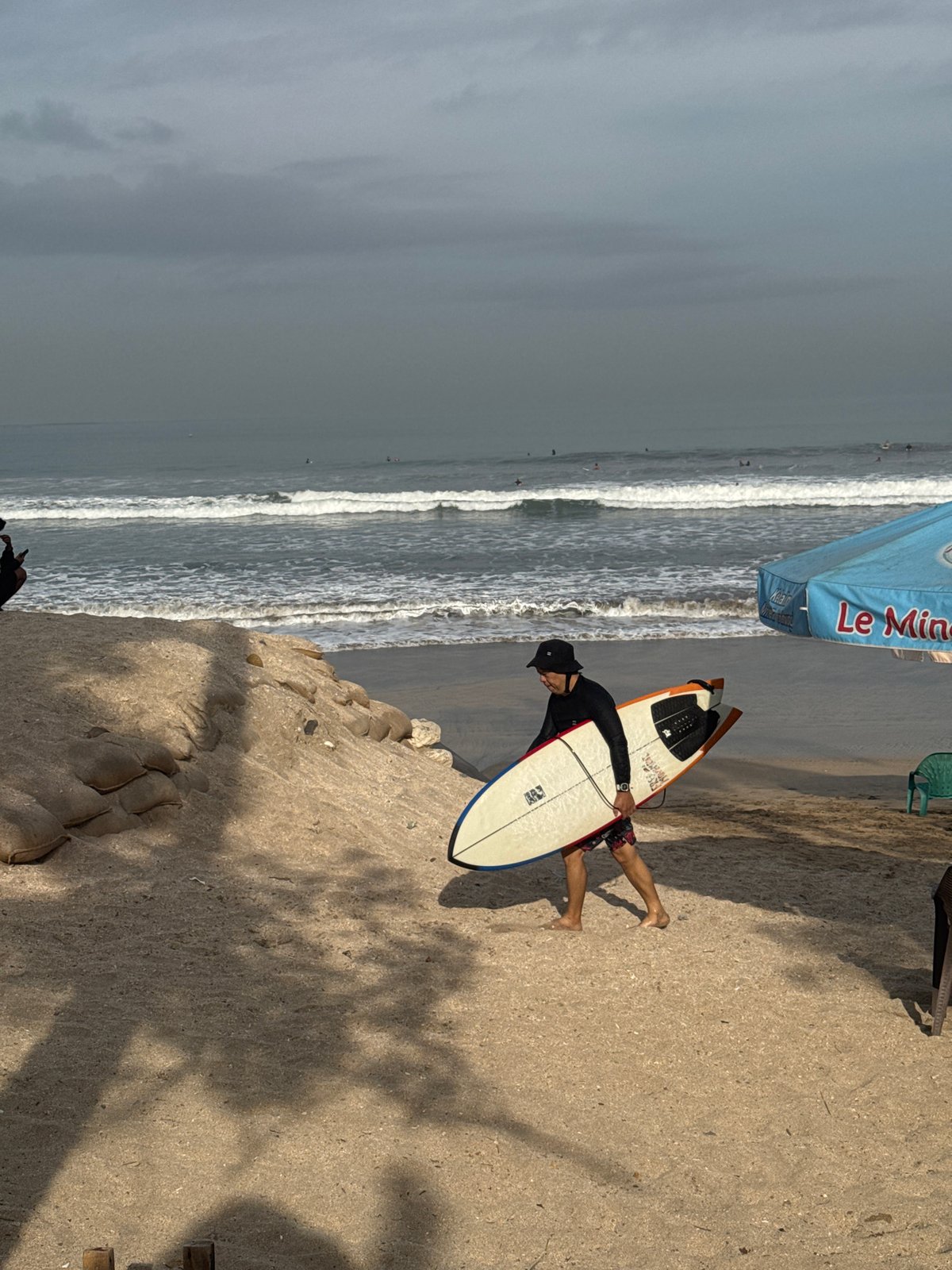 Surfers on Kuta Beach under overcast skies