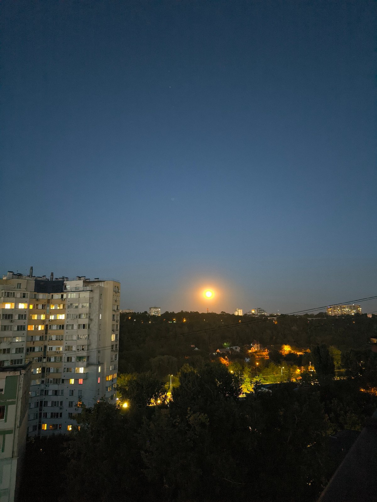 Chișinău residential skyline at twilight, moon rising over Soviet blocks