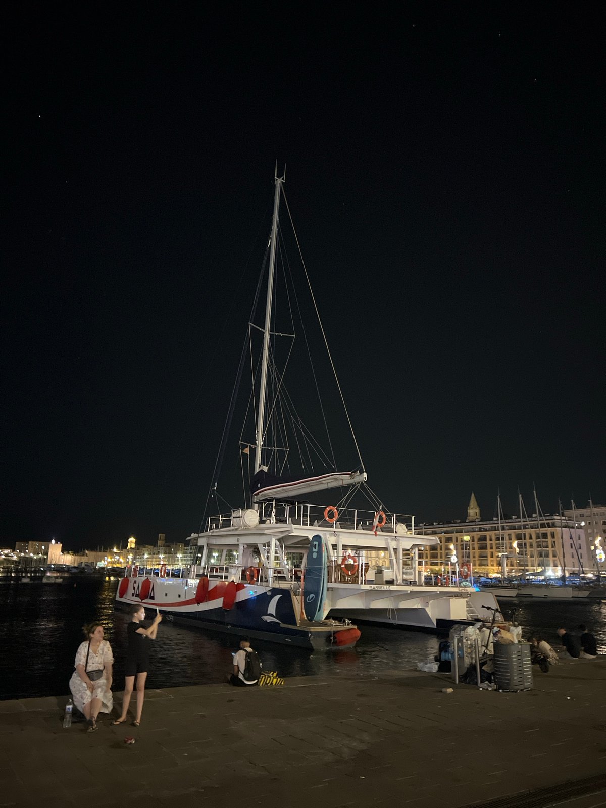 White catamaran docked at a Marseille marina after dark