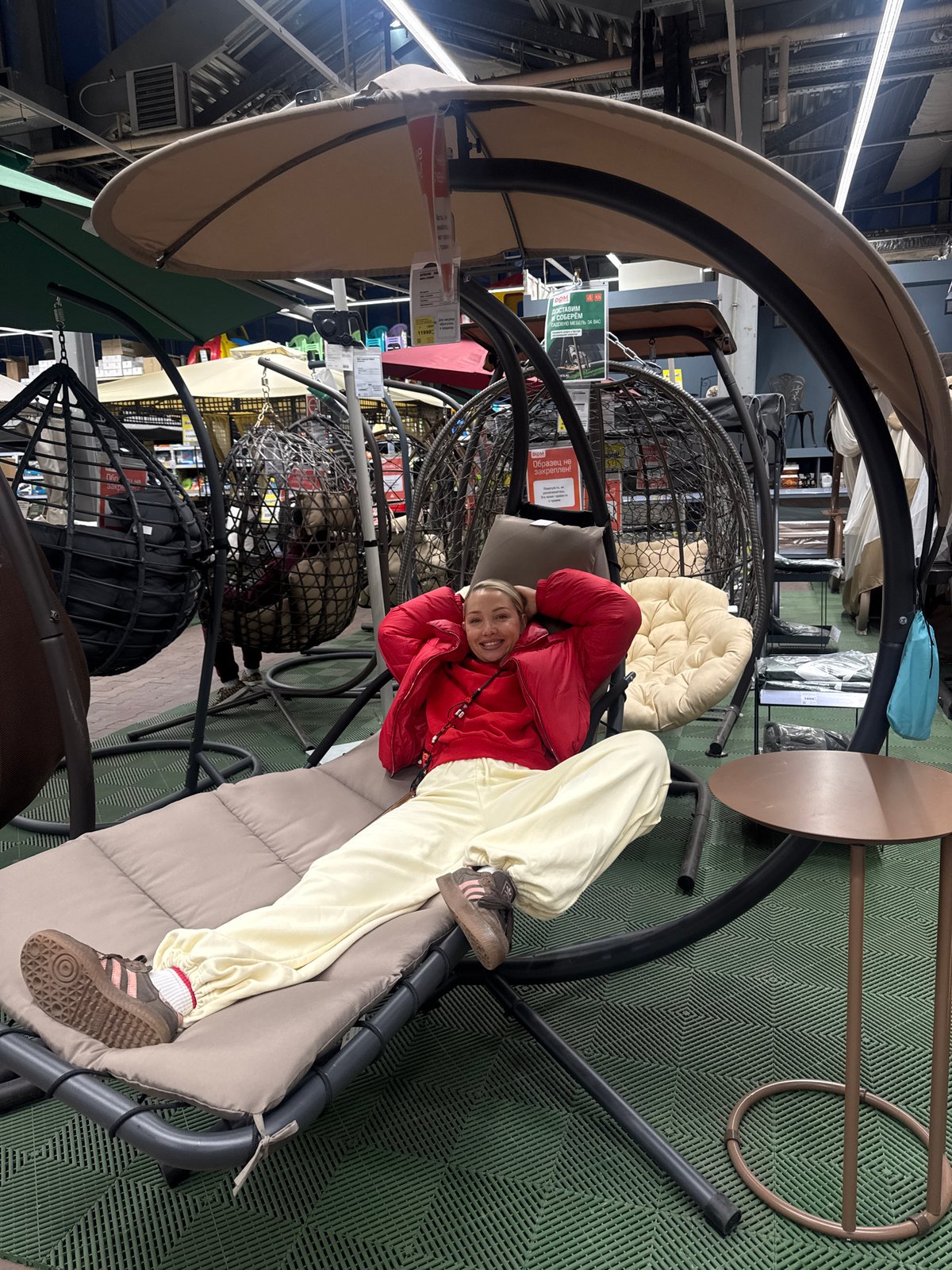 Woman relaxes on furniture display swing in Moscow store