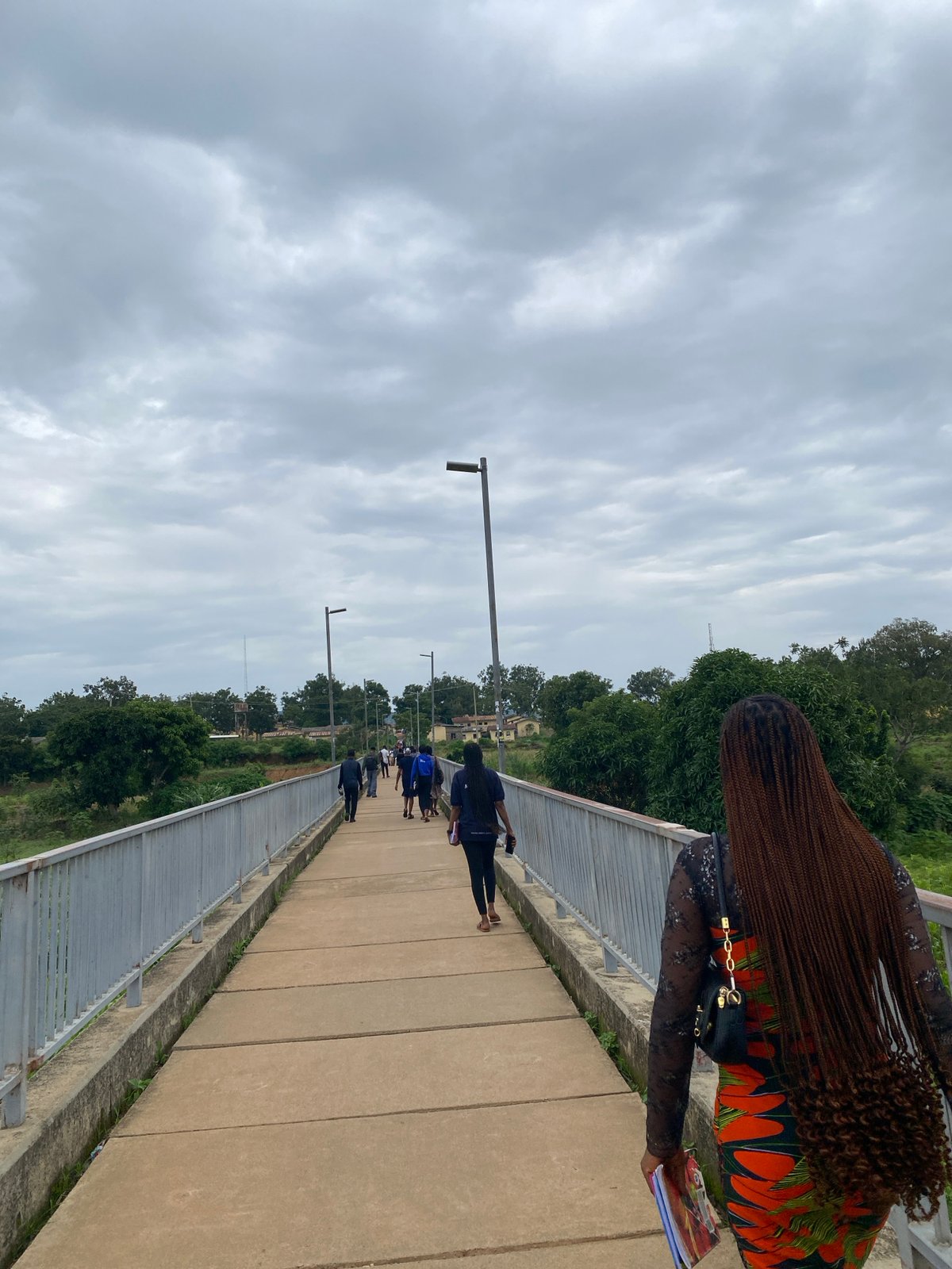 Pedestrian bridge and green hillside in a cloudy small town