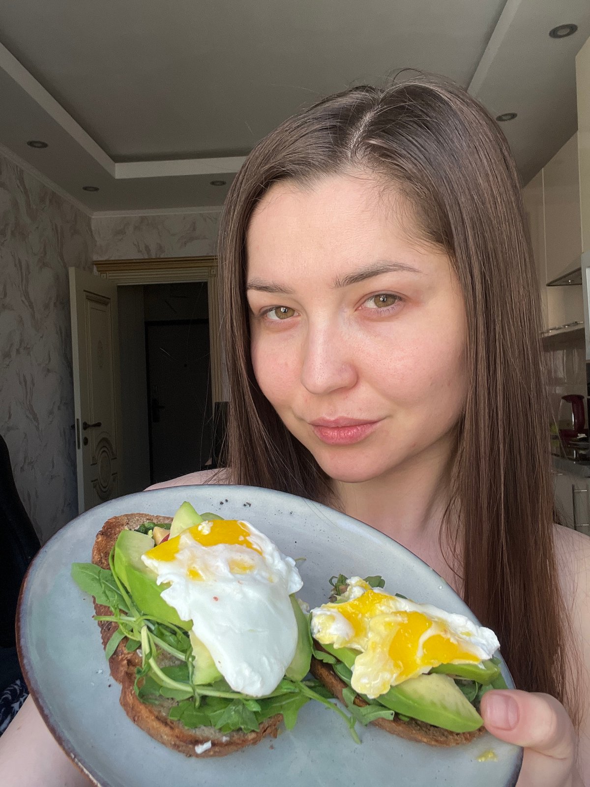 Woman enjoys homemade avocado toast breakfast in Khimki kitchen