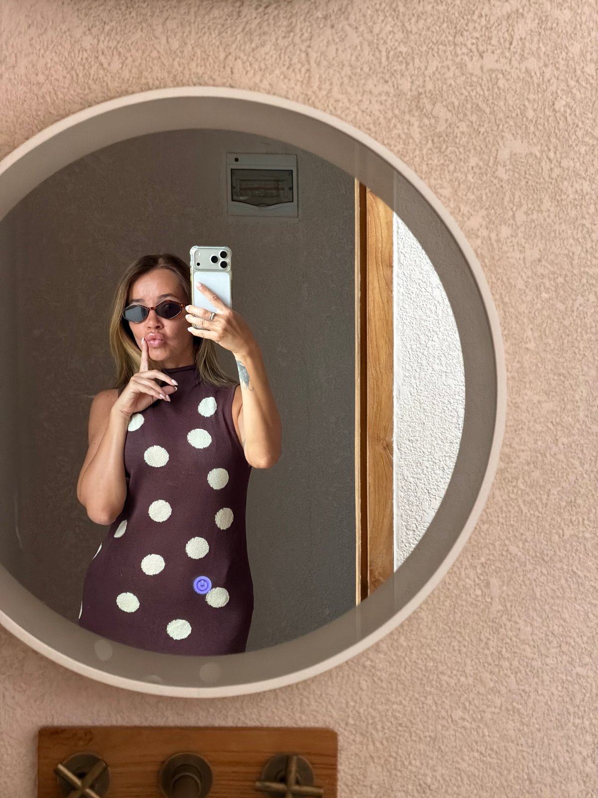 Mirror selfie in a warmly lit Mengwi bathroom, polka-dot dress