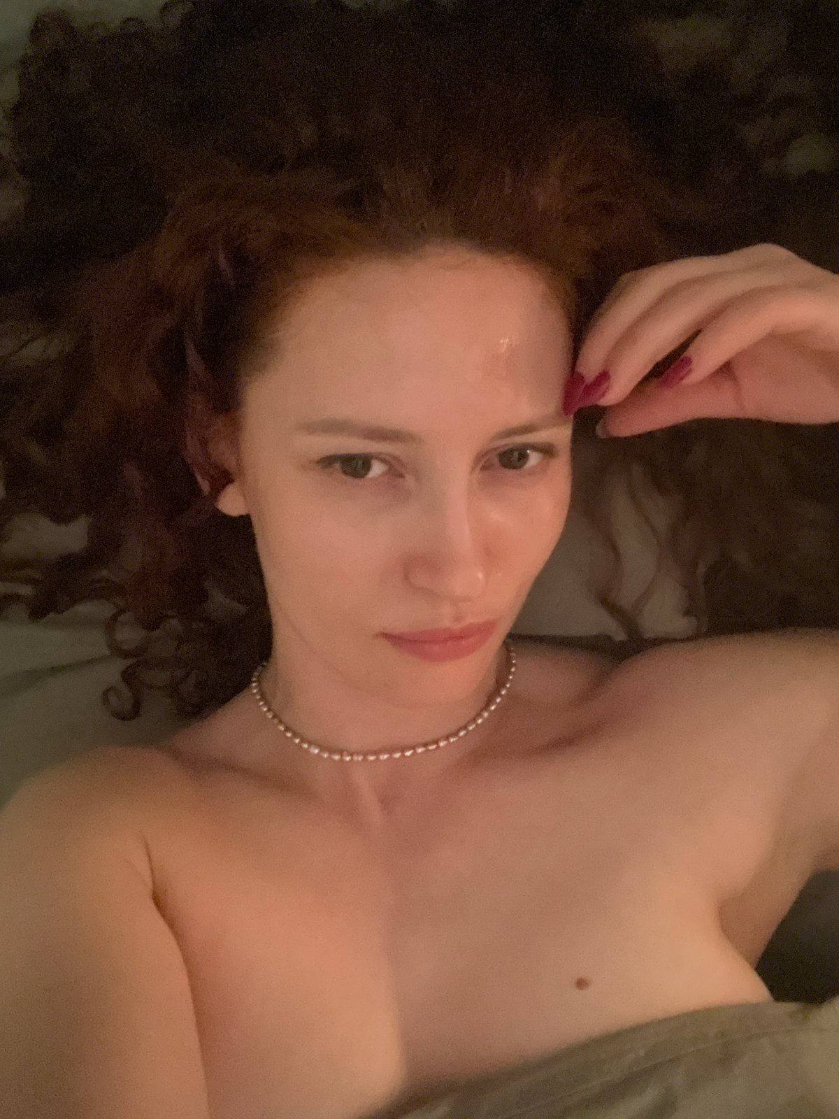 Red-haired woman resting with hand to forehead in Saint Petersburg