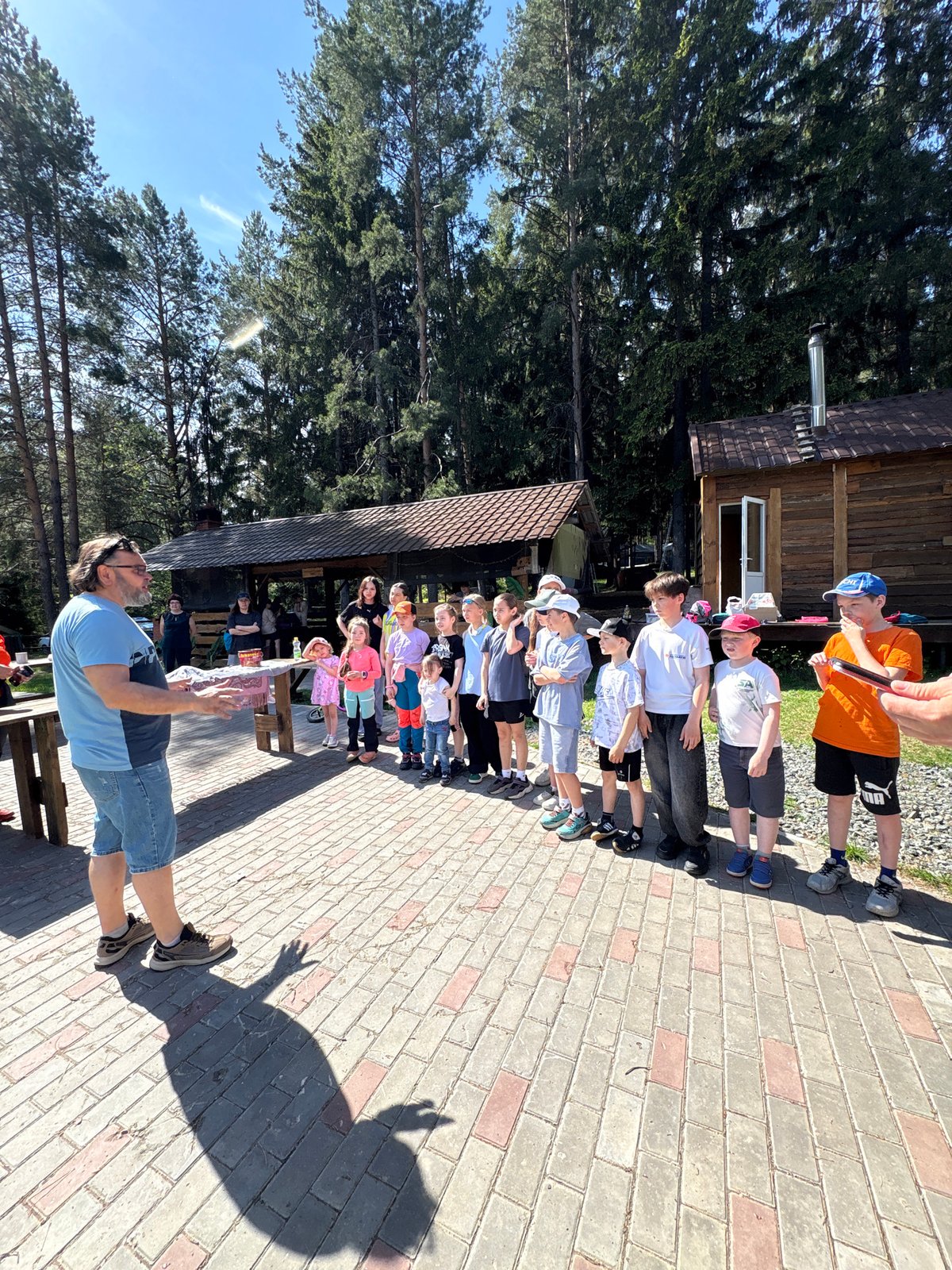 Adult addresses children outdoors in Прикамский on sunny morning