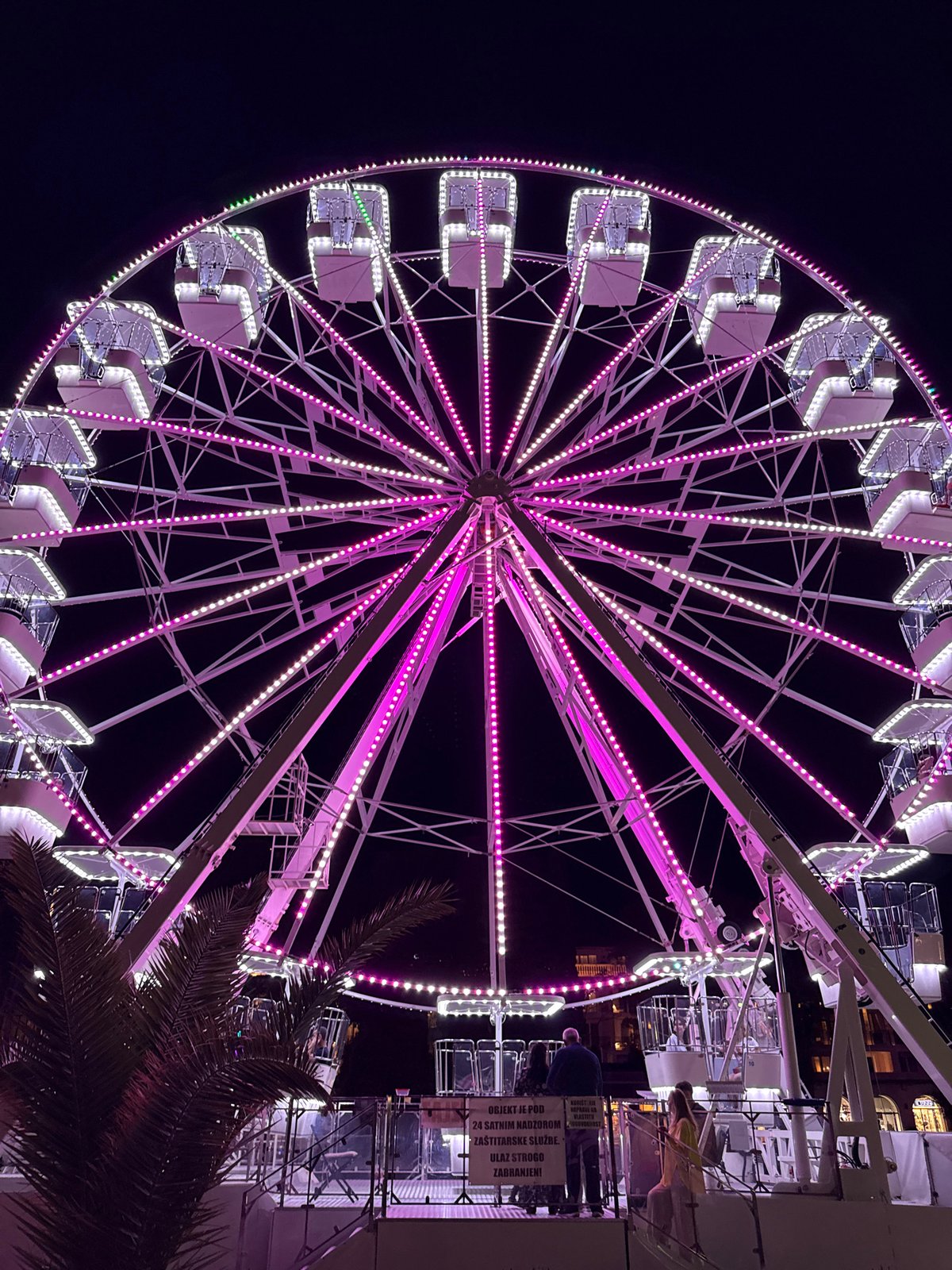 Evening scenes around Budva's illuminated waterfront Ferris wheel