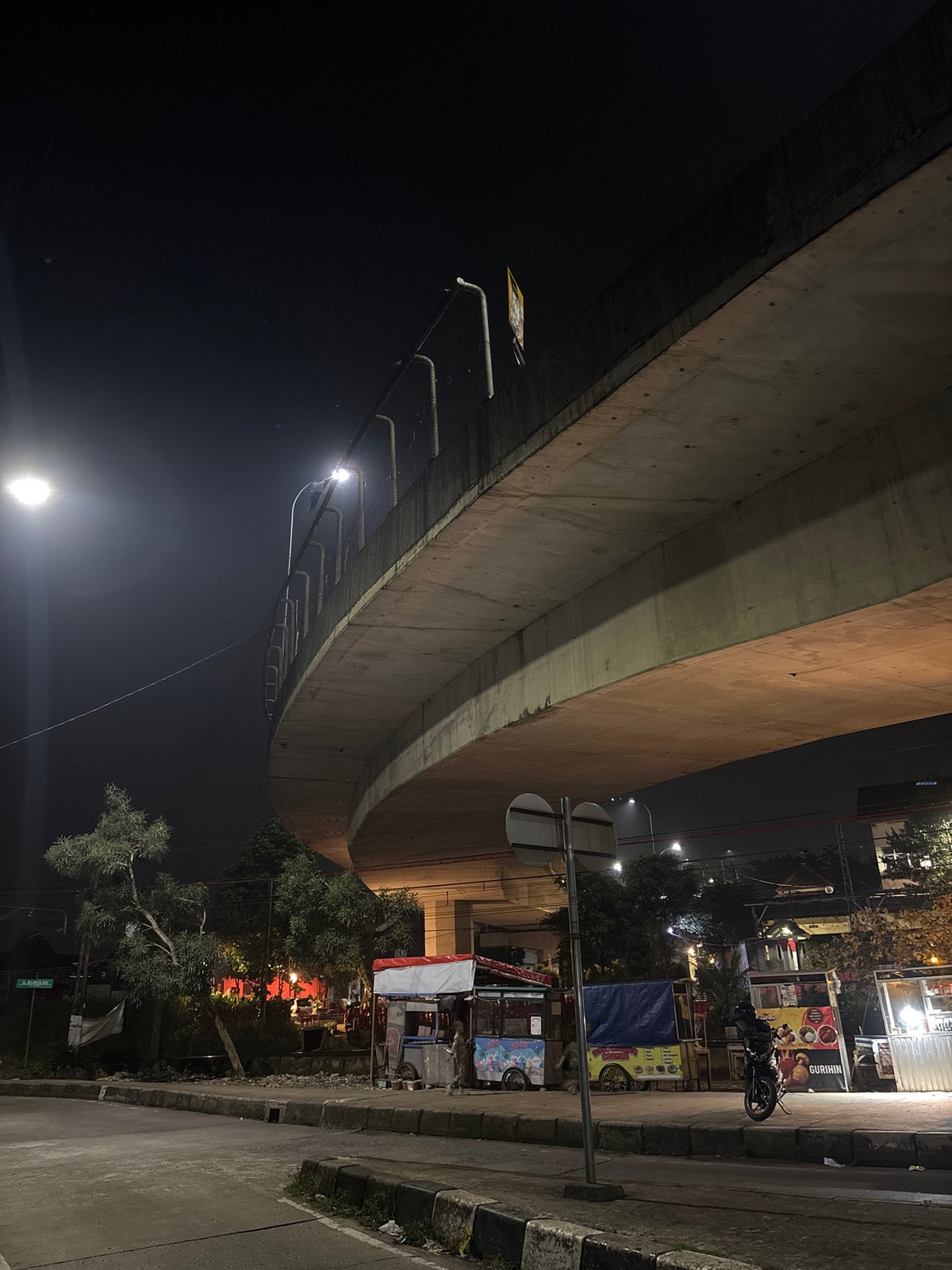 Street food vendors operate under Bogor overpass at night