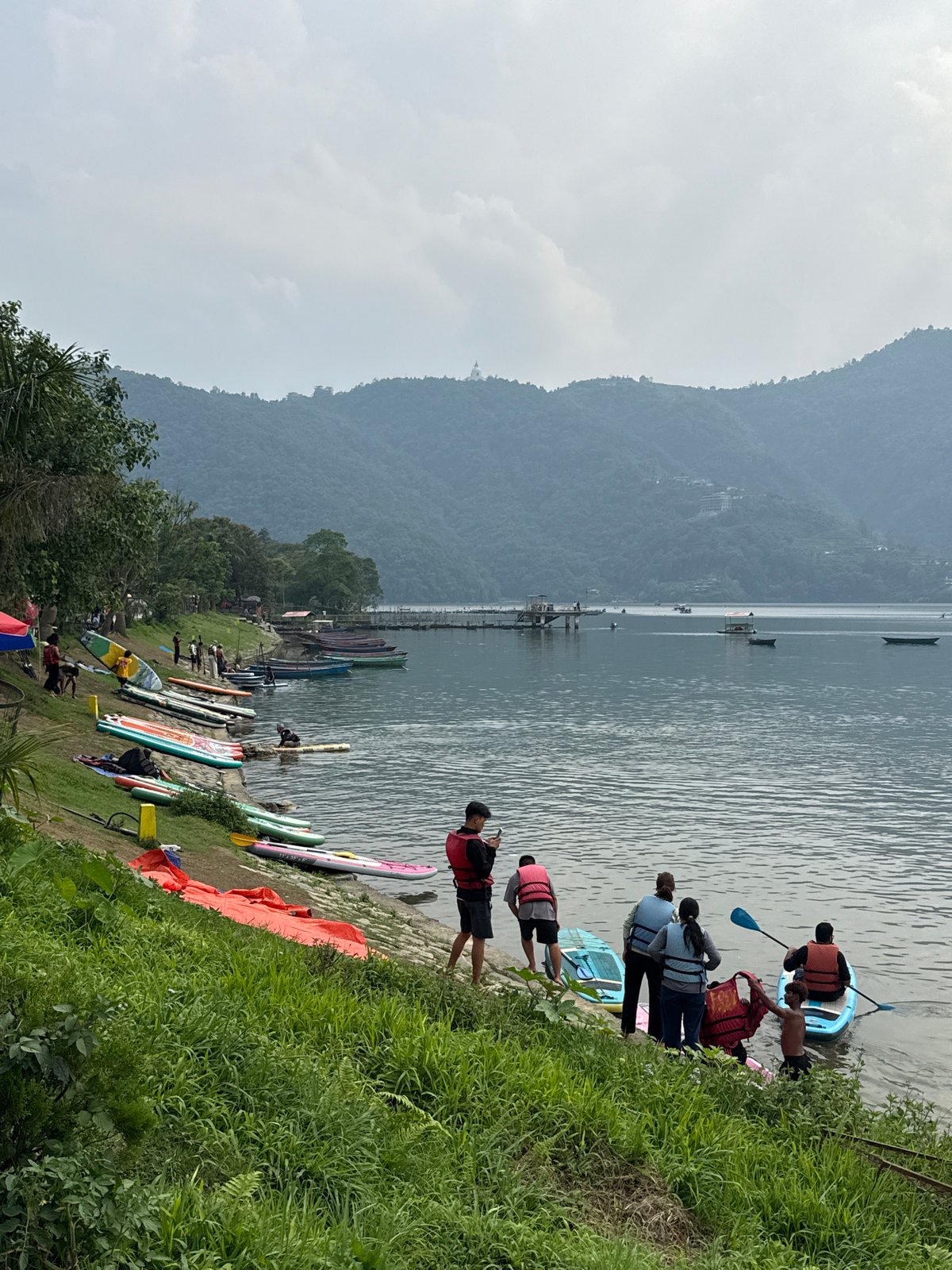 Paddleboarding activity observed at Nepal's Phewa Lake under cloudy skies