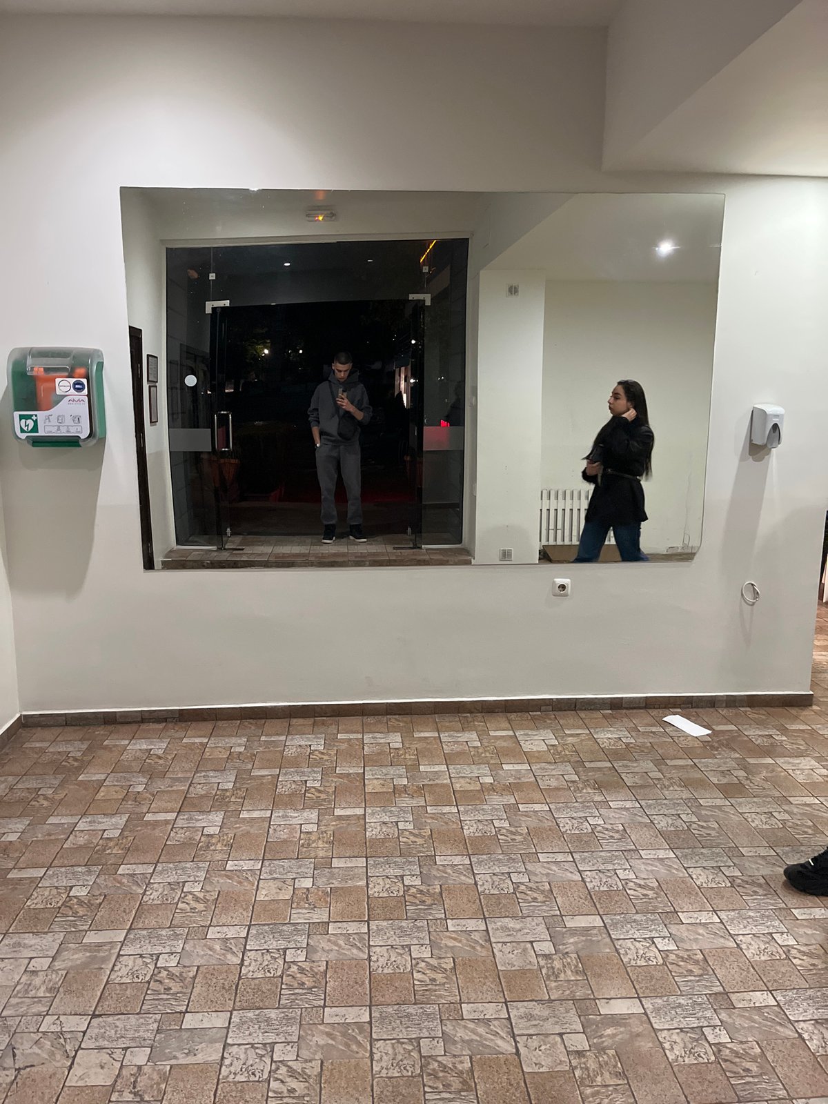 Mirror reflection captures two people in Karlovo building lobby