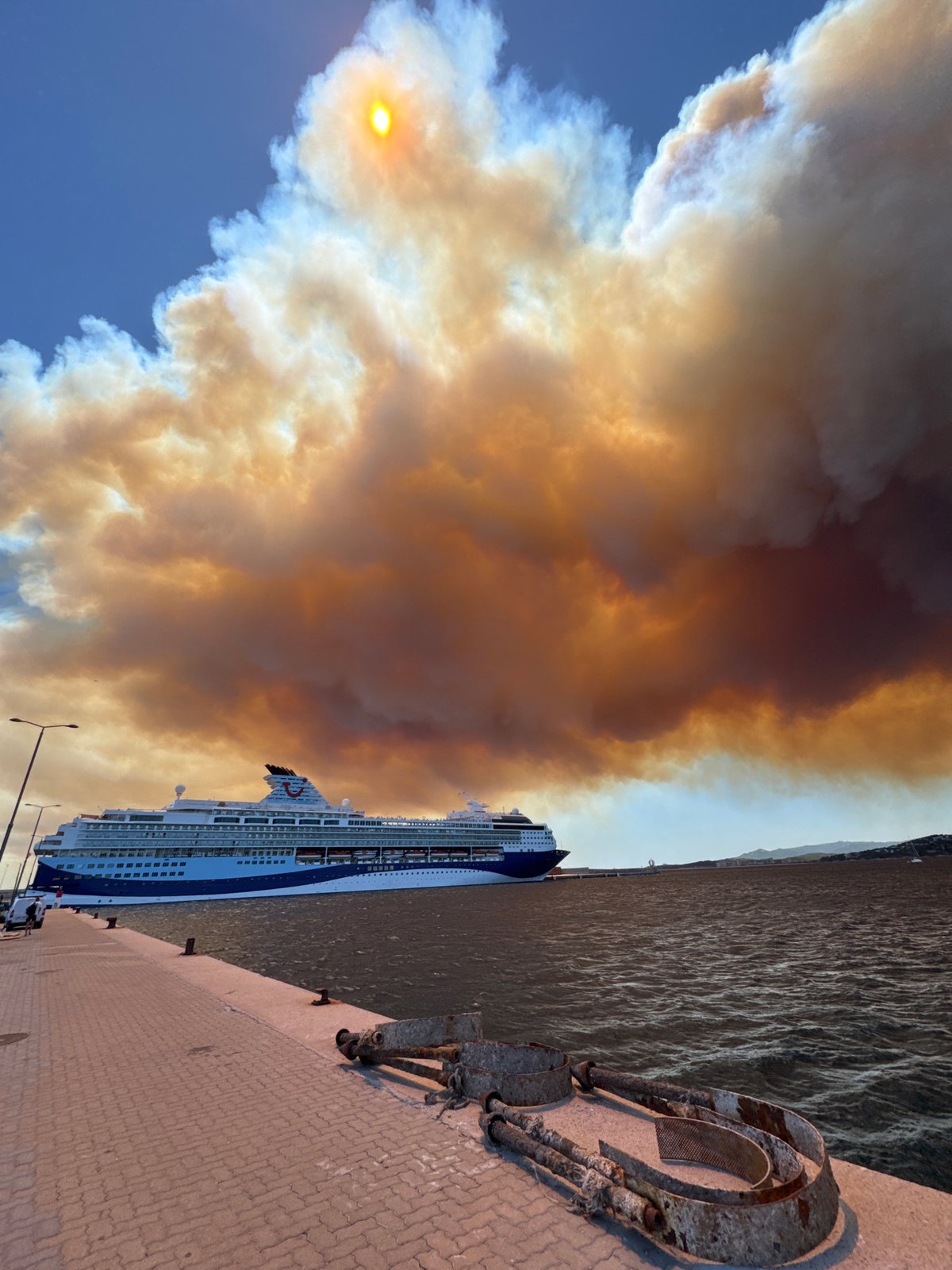 Wildfire smoke blankets Palamós harbor over docked cruise ship