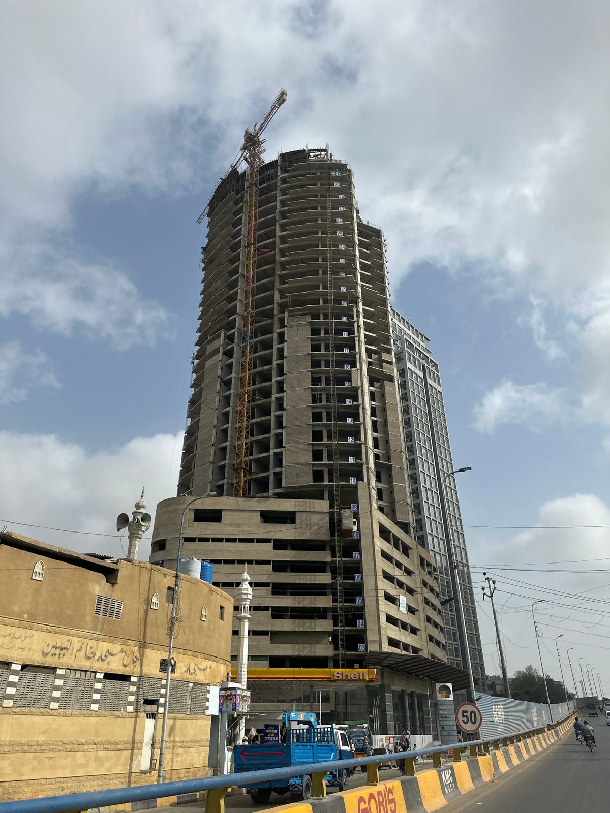 Construction site and street-level motorcycle scene in Karachi