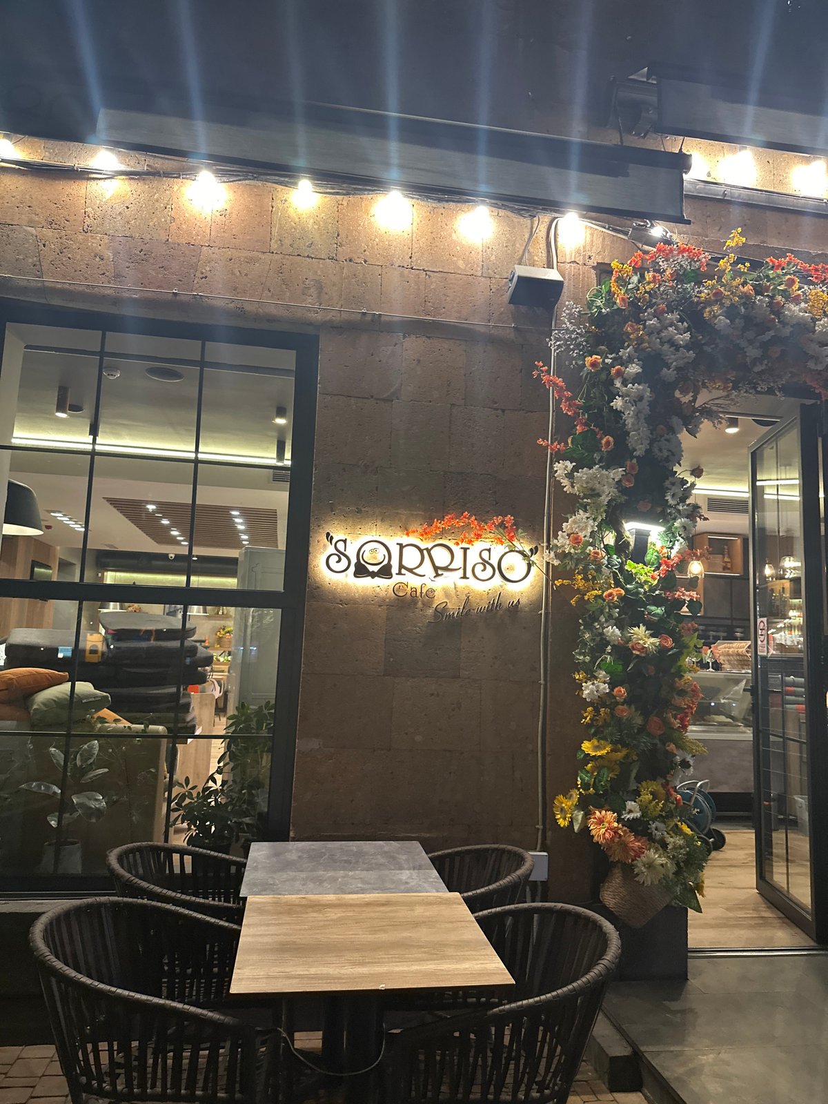 Illuminated Qpiso Cafe captured with flowers and visible interior