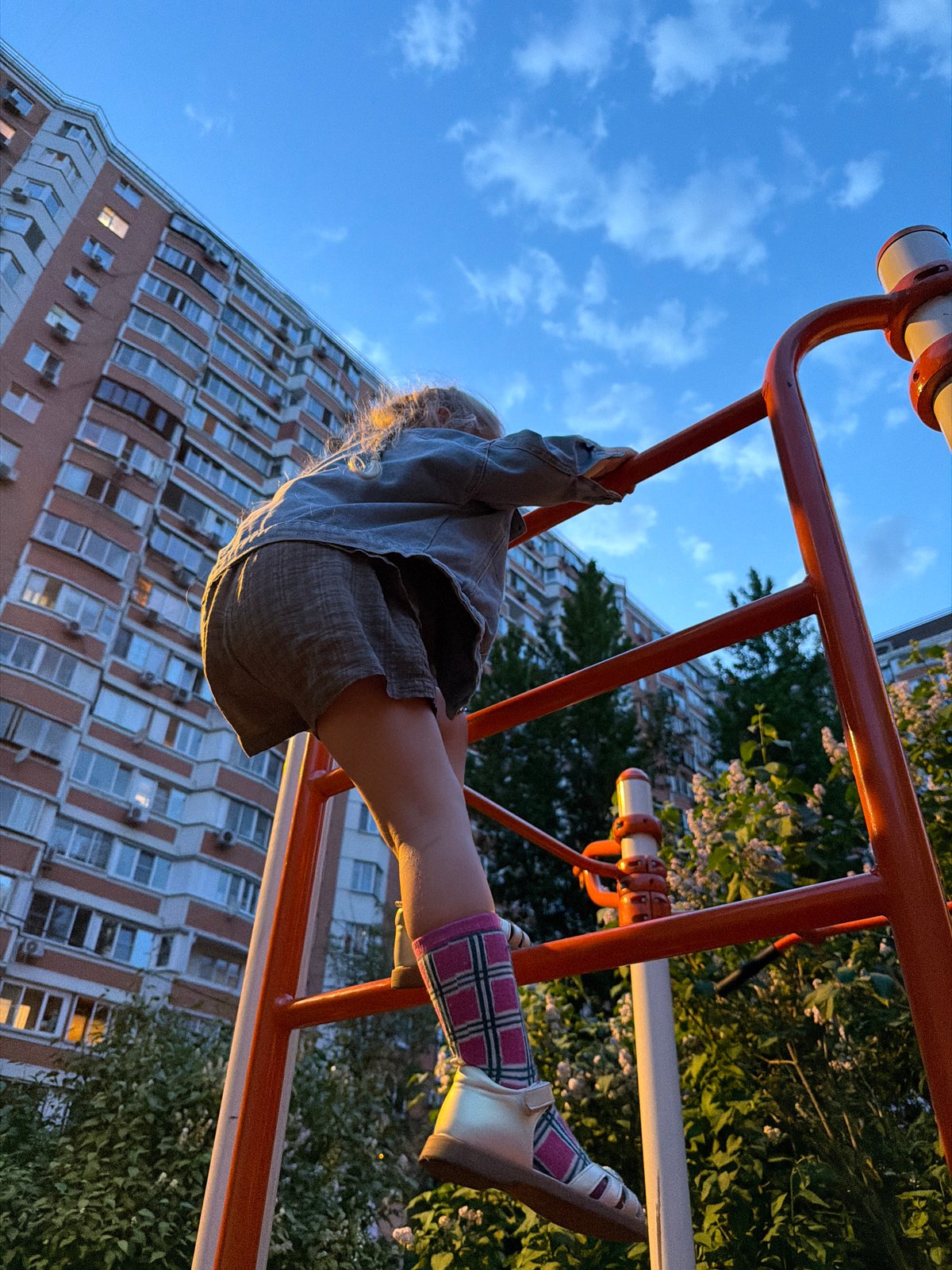 Child plays upside down on jungle gym in Moscow
