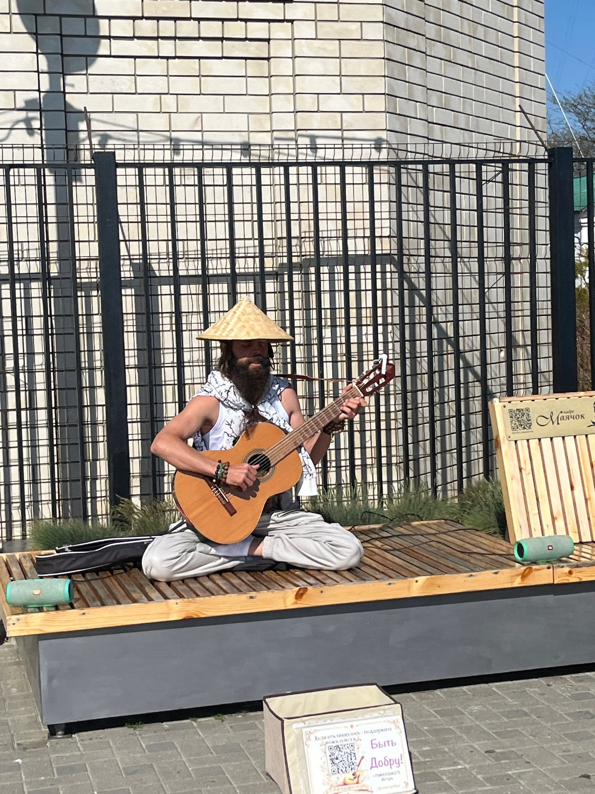 Street musician performs guitar near iron fence in Anapa