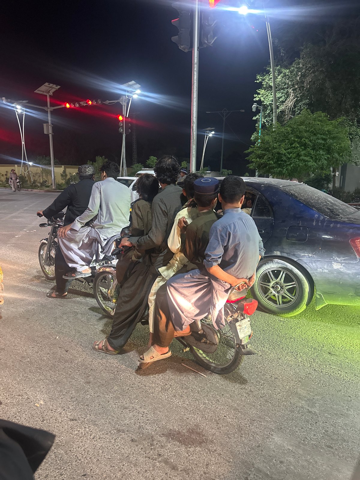 Young men in traditional attire gather on nighttime street