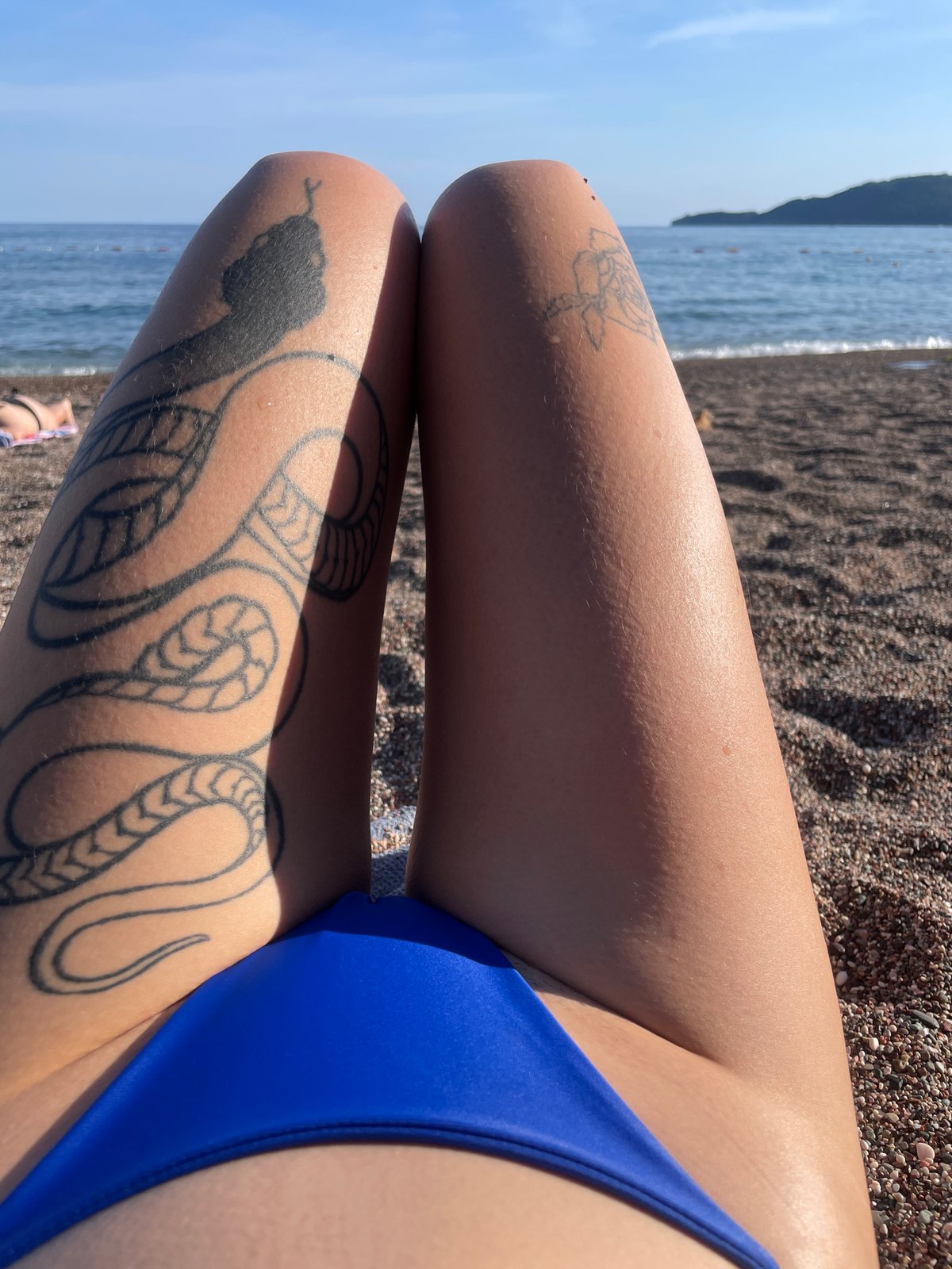 Tattooed woman sunbathing on Rafailovići beach, Montenegro
