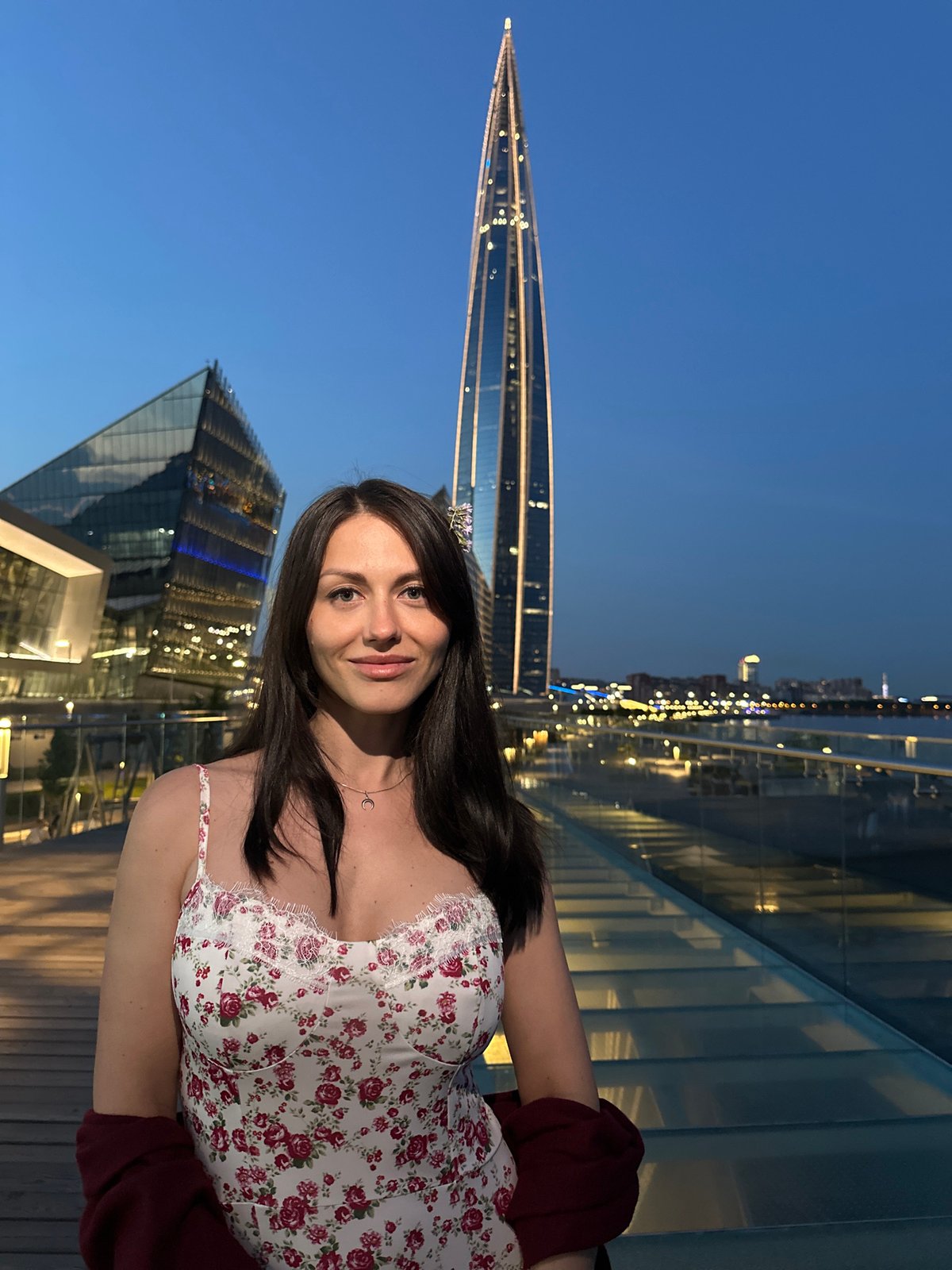 Woman poses for extended photo session near Lakhta Center at dusk