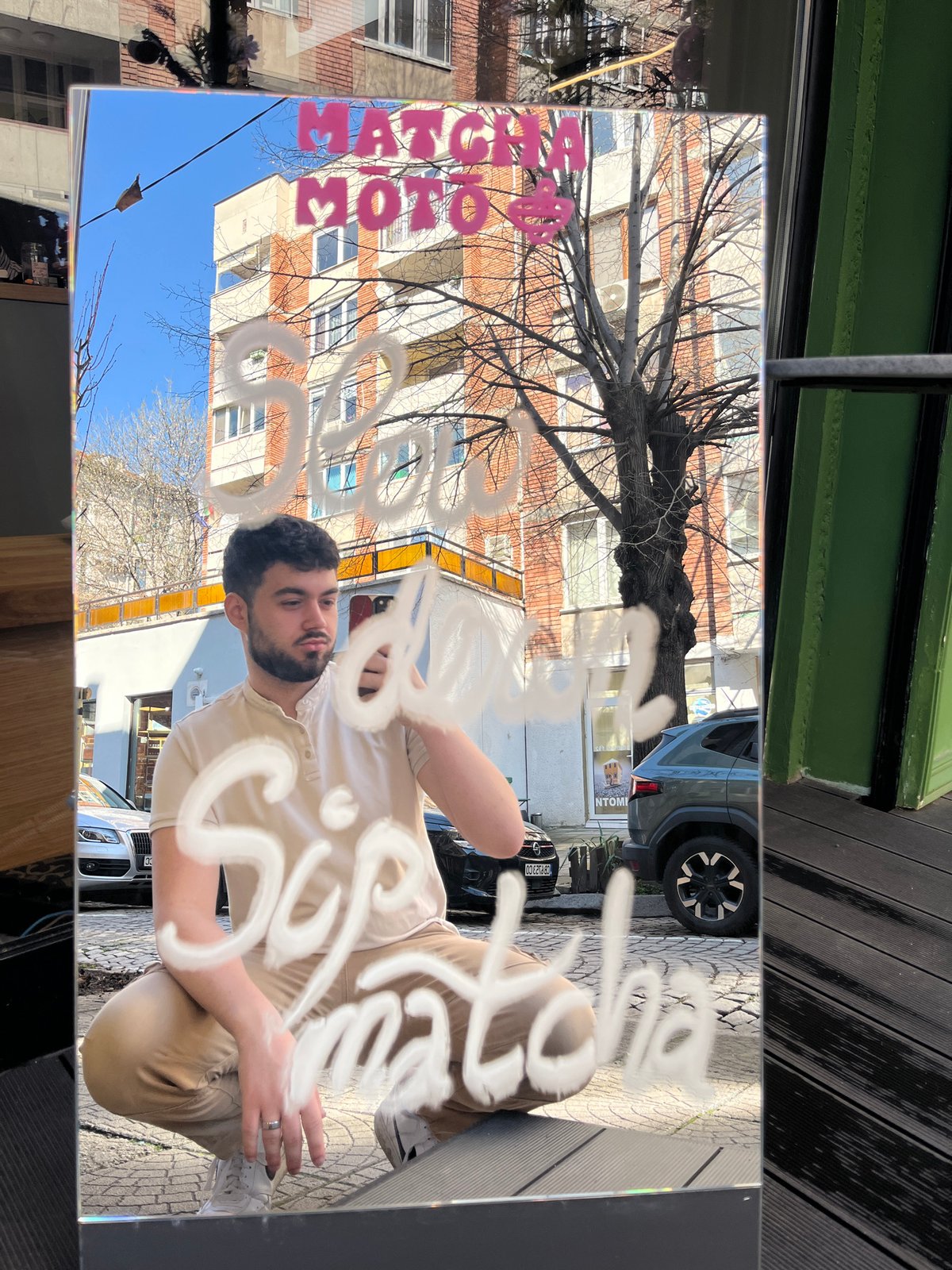 Man in tan clothing reflected in Sofia storefront glass