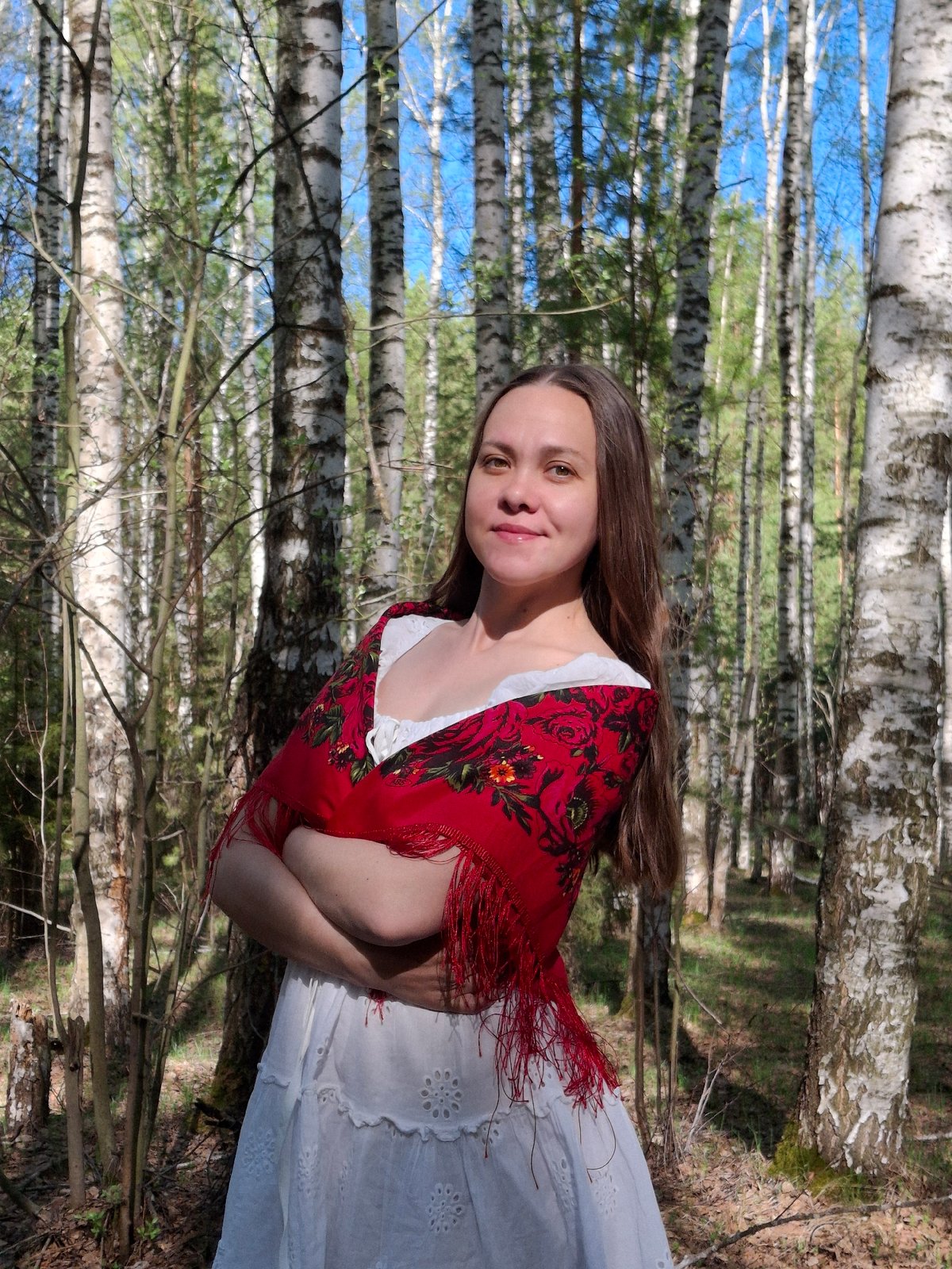 Woman in white dress, red shawl spotted in birch forest