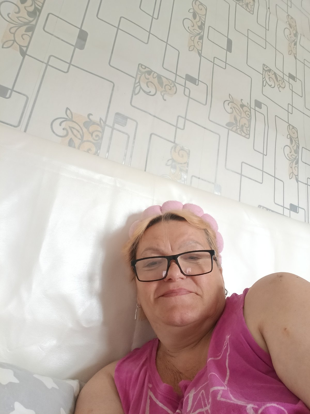 Woman in pink outfit relaxes in bedroom, Красный Маяк
