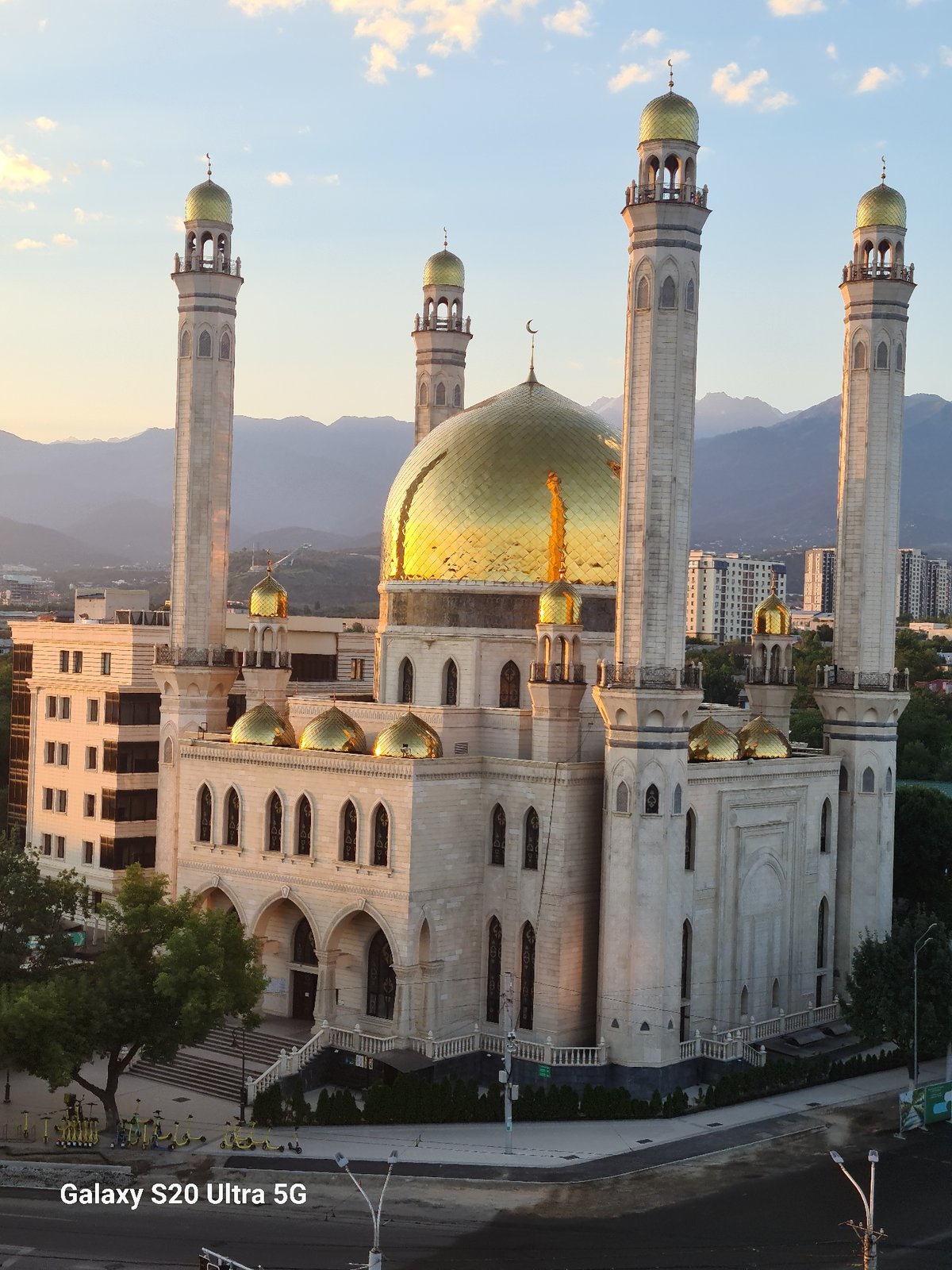 Almaty's Central Mosque at golden hour, mountains behind
