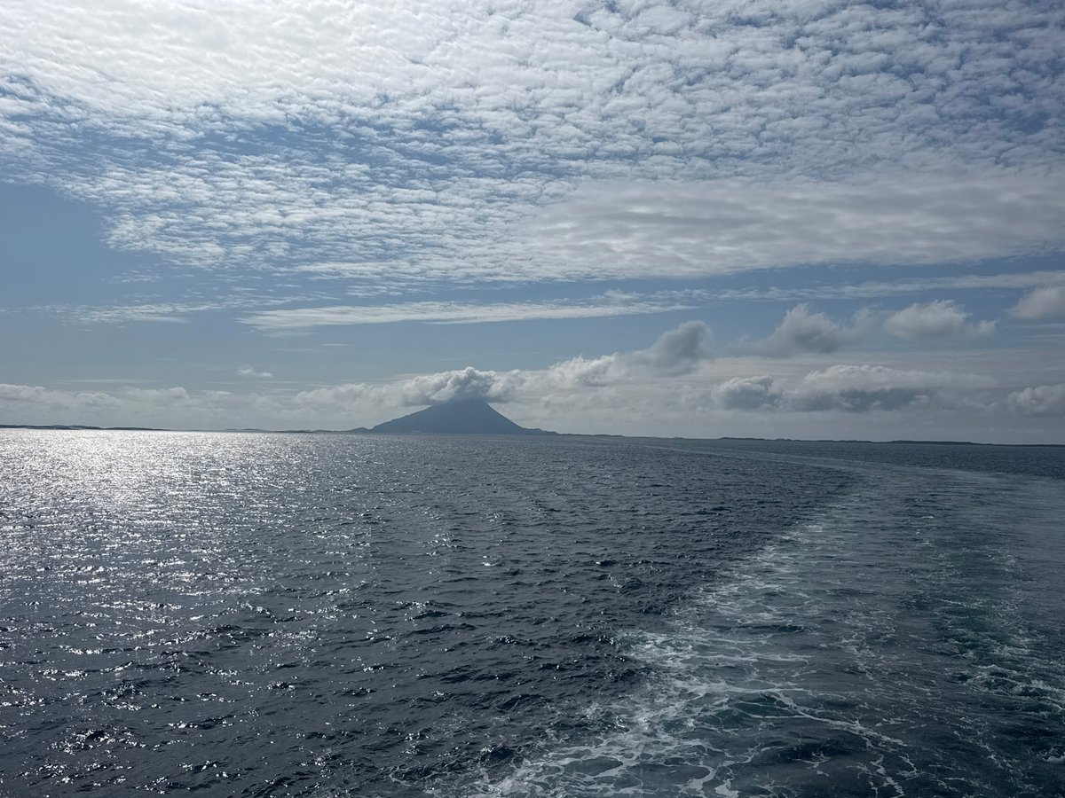 Ferry crossing open Norwegian waters past a lone coastal peak