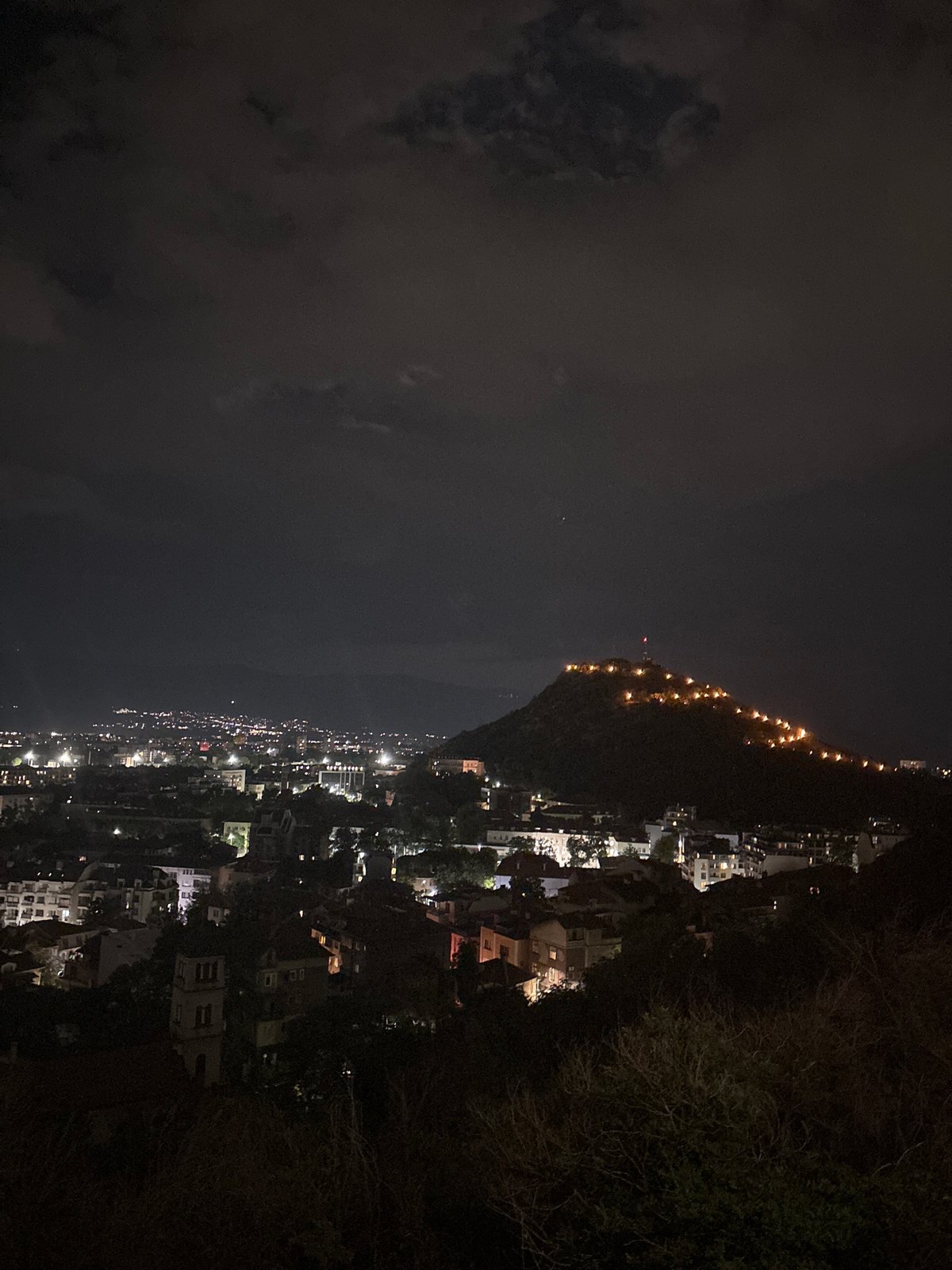 Coastal hillside town glows faintly in the night
