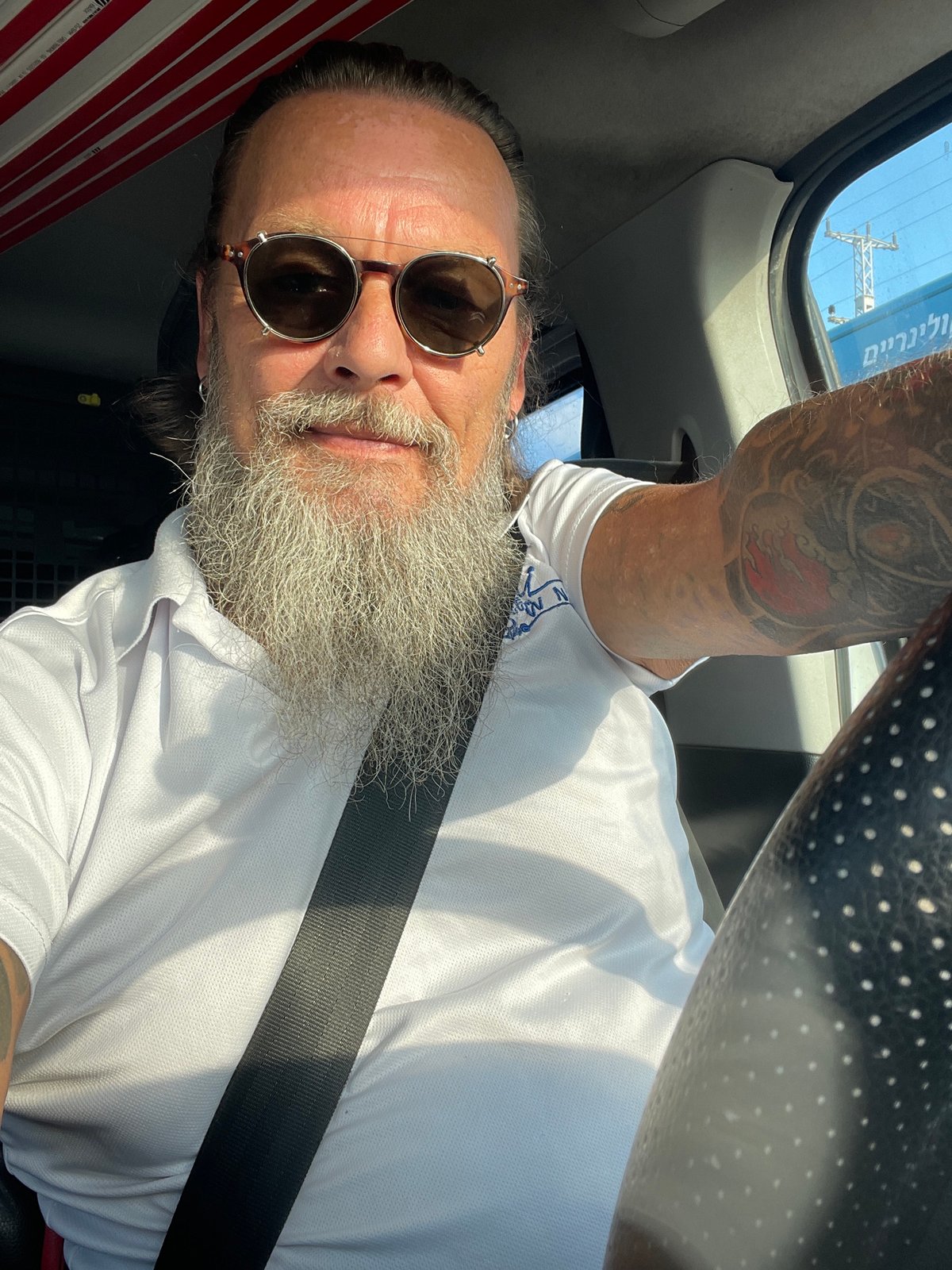 Driver's seat selfie in Beit Yehoshua, gray beard and shades.