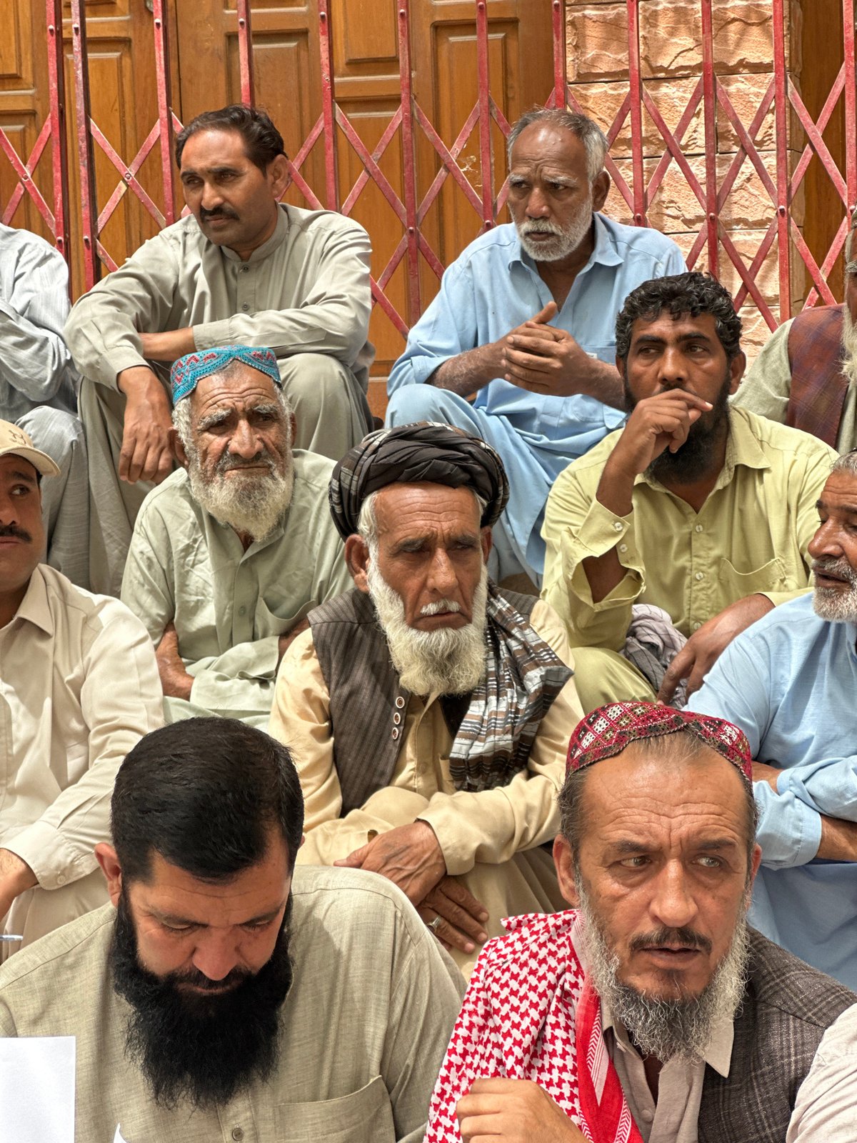 Protest outside gated building in Quetta, signs and speaker present