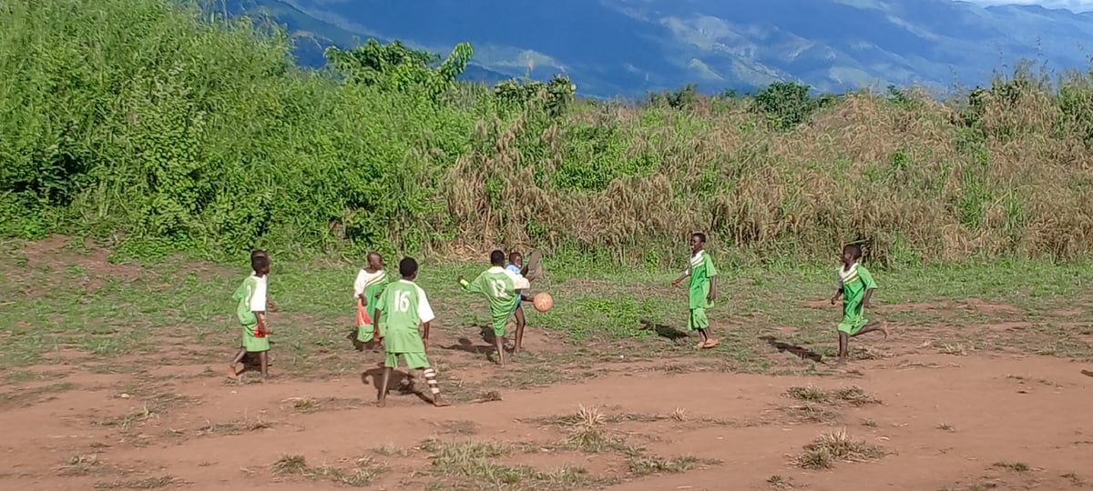 Children play informal soccer on dirt field in Ngalula, DRC