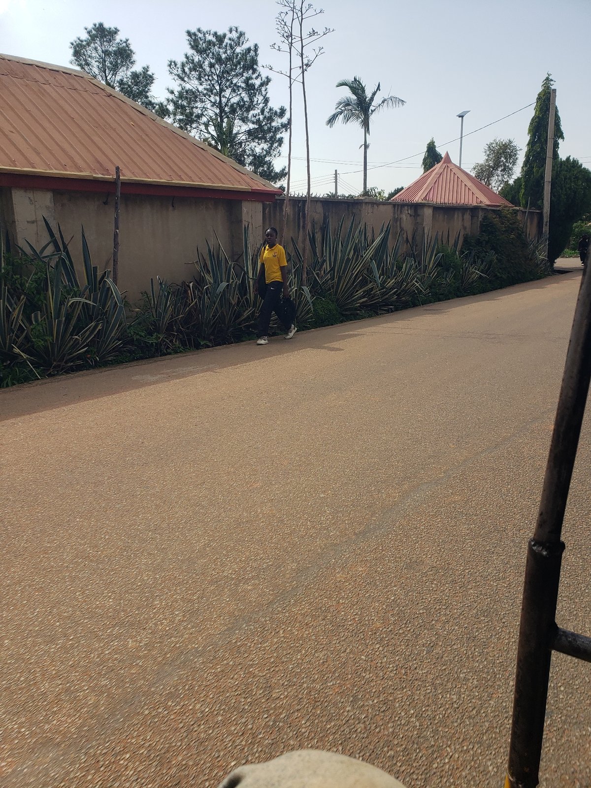 Pedestrians walk along paved road in Gura Top, Nigeria