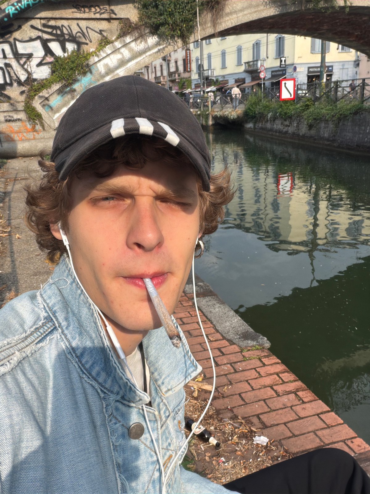 Young person relaxes by canal in Milan's Navigli district