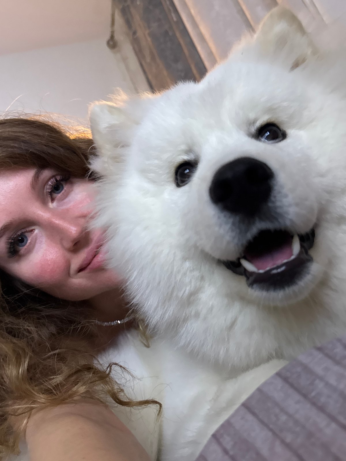 Woman photographed with white dog on bed in Chaikovsky