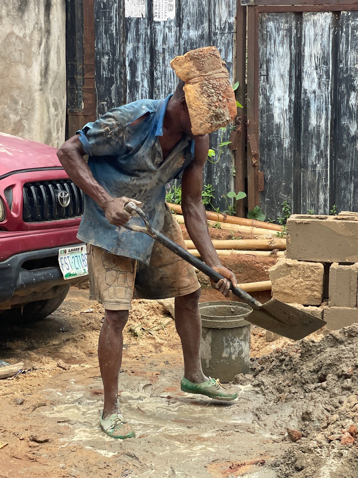Construction worker carries brick on head in Onitsha