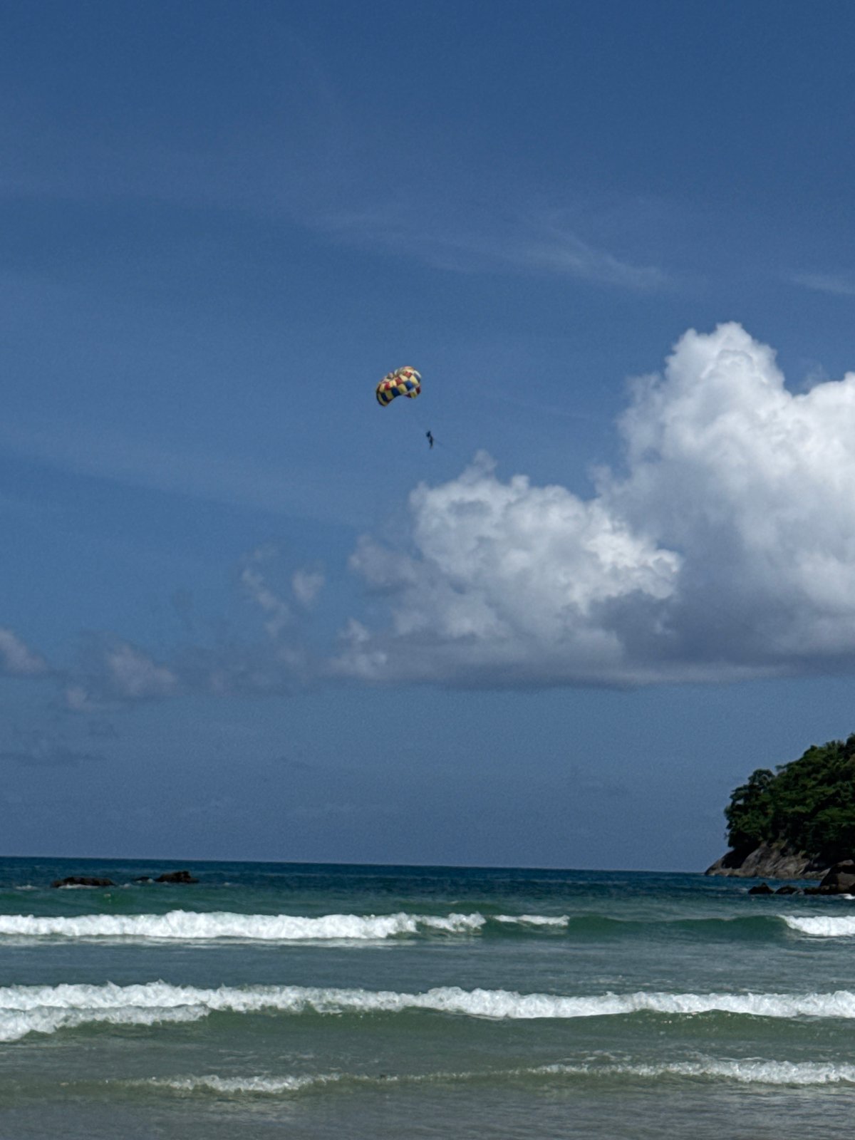 Karon Beach on a clear morning: parasailing, calm water, tuk-tuk waiting