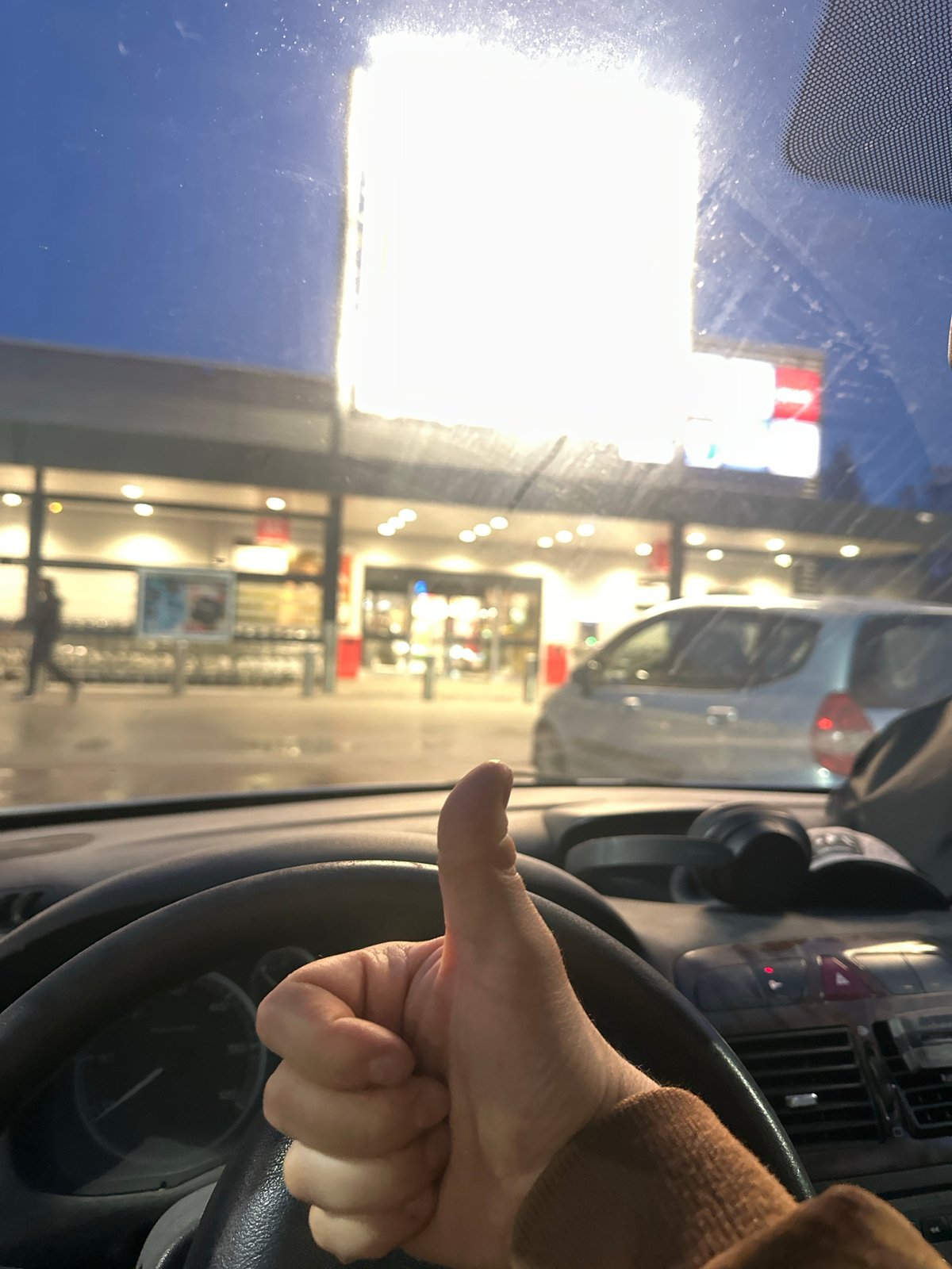 Driver gives thumbs-up gestures in car during rainy night in Sofia