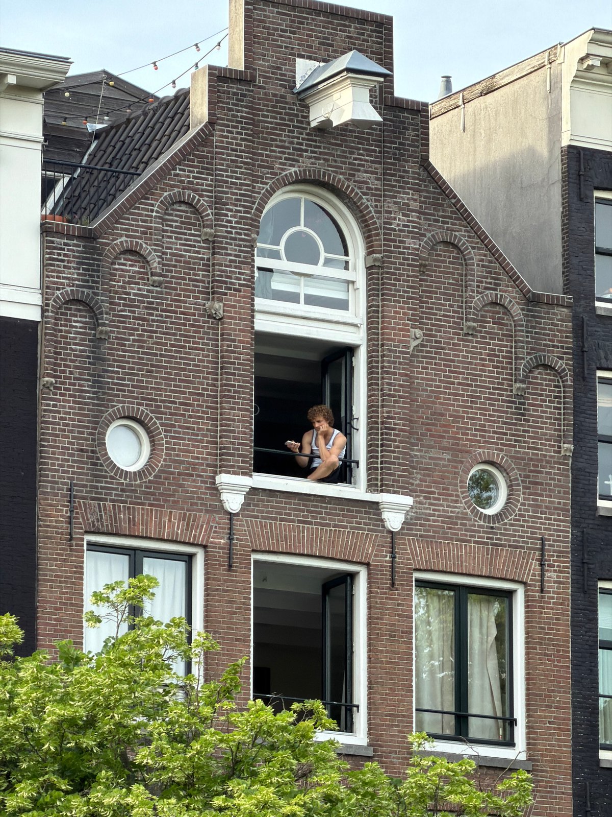 Woman leans from window of Amsterdam canal house