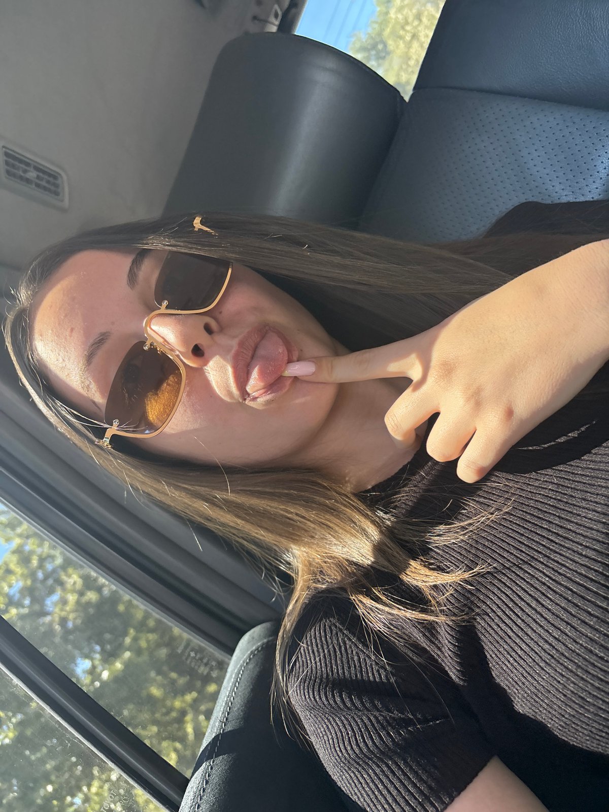 Woman poses playfully in car with decorative manicure in Burgas