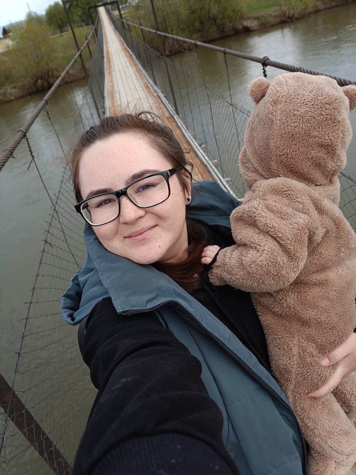 Woman, baby in bear costume pose on Russian bridge
