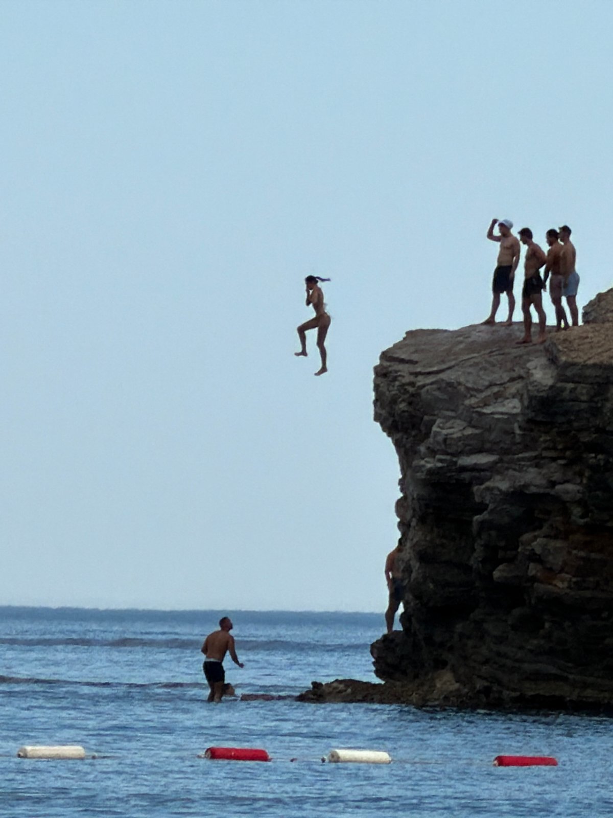 Cliff diving off Budva's rocky Adriatic coastline on a summer afternoon.