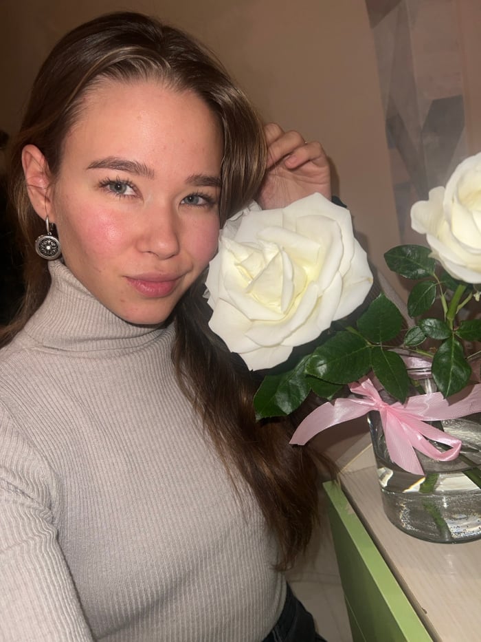 Woman photographed with white rose in Krasnoyarsk indoor setting
