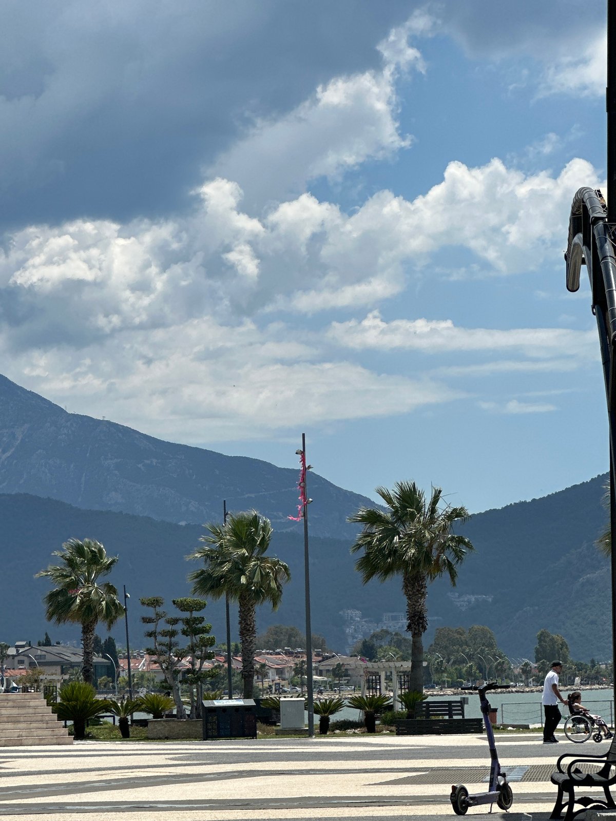 Tourist takes donut selfies on Fethiye promenade as children play