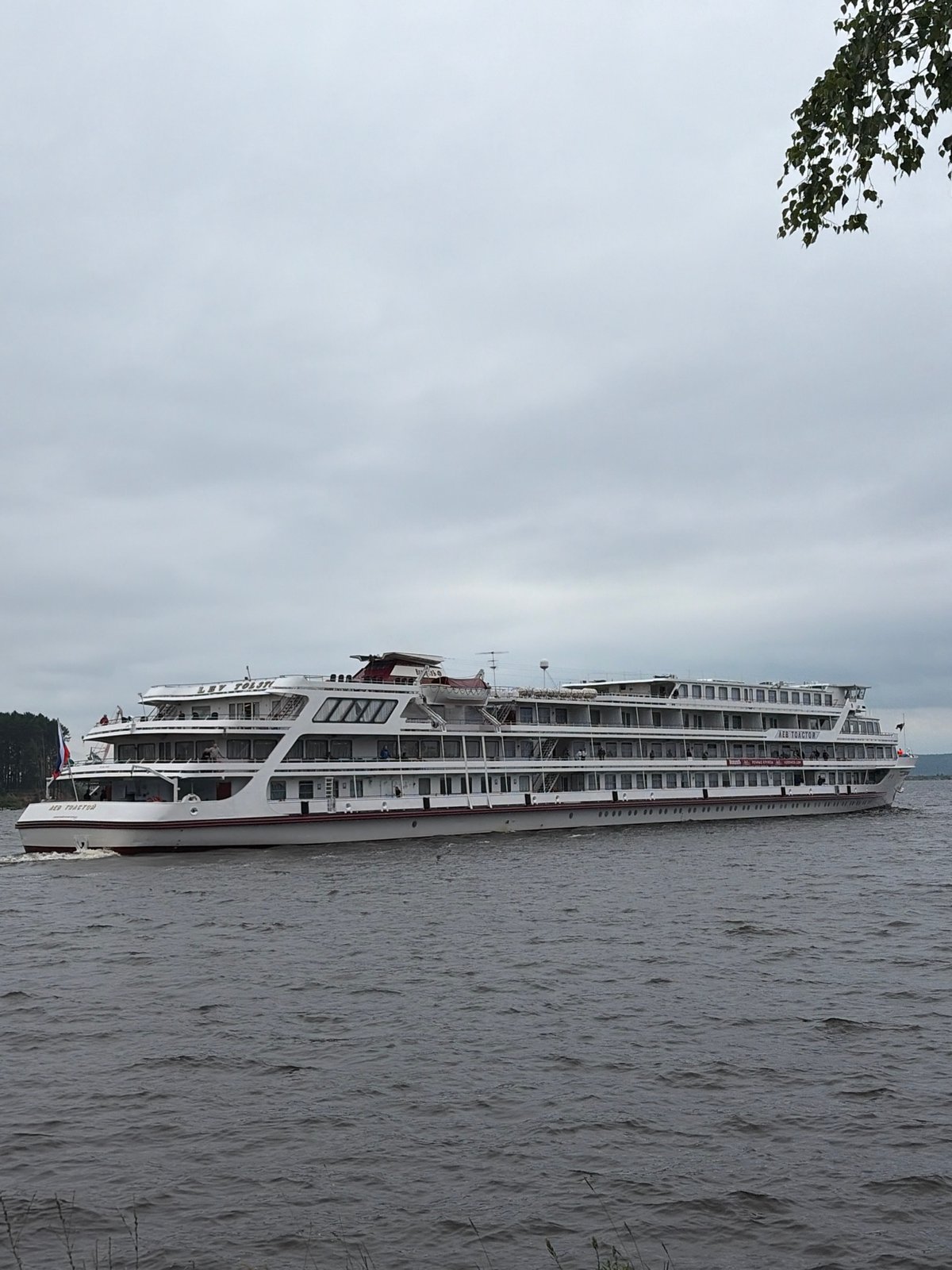 River cruiser Lev Tolstoy passes Chaikovsky on a grey afternoon