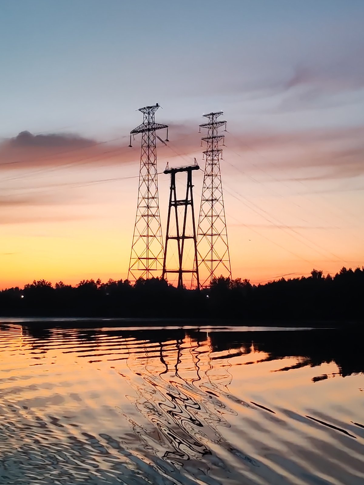 Sunset illuminates power pylons along Konakovo river at dusk