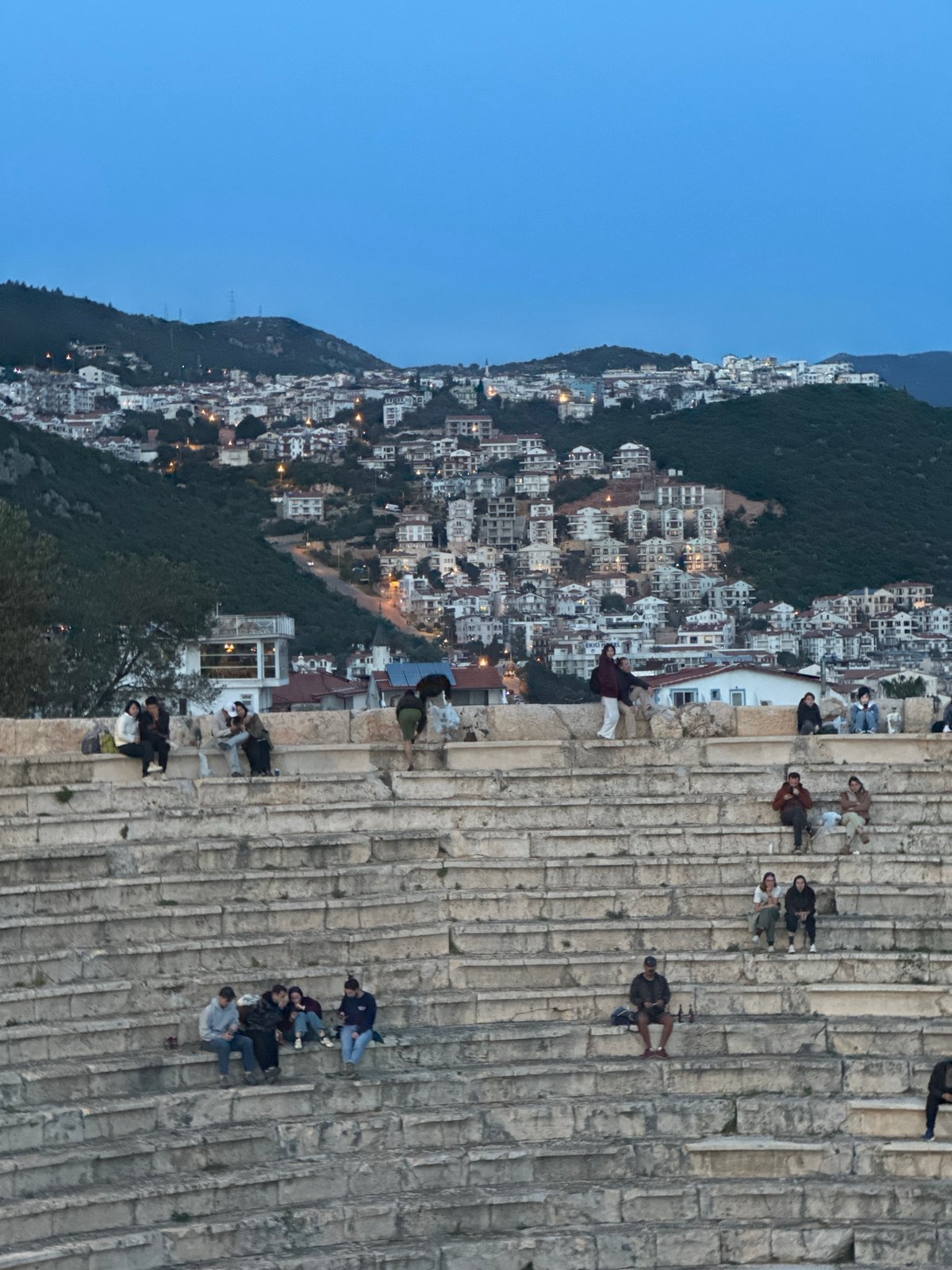 Tourists gather at ancient Kaş theater overlooking Mediterranean at dusk